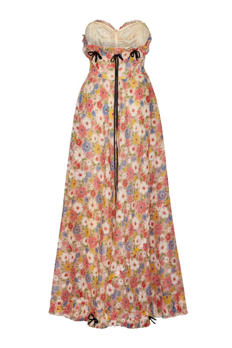 Stunning full-length summer dress in printed organza with the prettiest pastel florals.  This strapless dress is boned for support and is fully lined in ivory.  It all features a pretty frill around the top and bottom with cute little black velvet