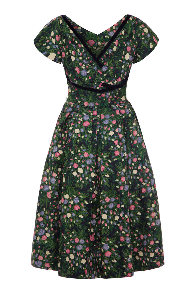 A beautiful 50’s dress typical of the era, this piece comes in forest green silk with a pretty rose bud/bouquet floral print.  The skirt has a layer of netting for extra fullness and there is a contrasting black velvet trim around the neckline and