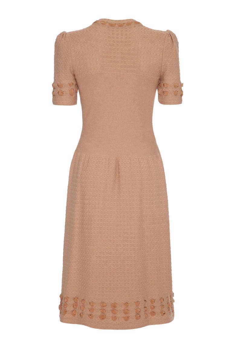 Terribly sweet and easy to wear this dress features a pretty ribbon trim with a textured skirt and sleeves. The ribbon continues around the neckline to tie into a bow at the front with round buttons to fasten. The slightly dropped waist is very