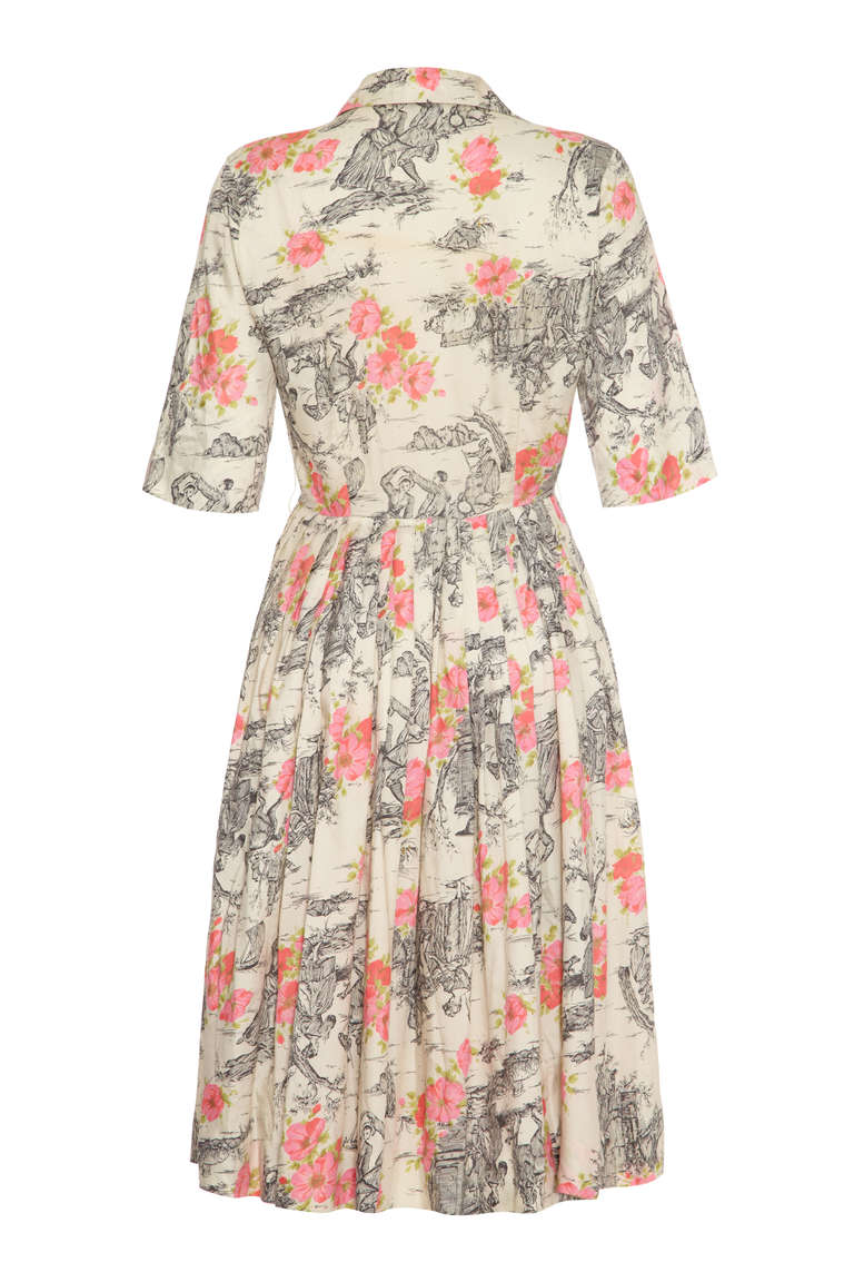 Very Pretty 50’s dress with a fun and unusual print featuring monochrome country scenes and pink and green florals.  With a full skirt pleated at the waist, button up front and ¾ sleeves this is a very wearable shirt dress for any occasion.