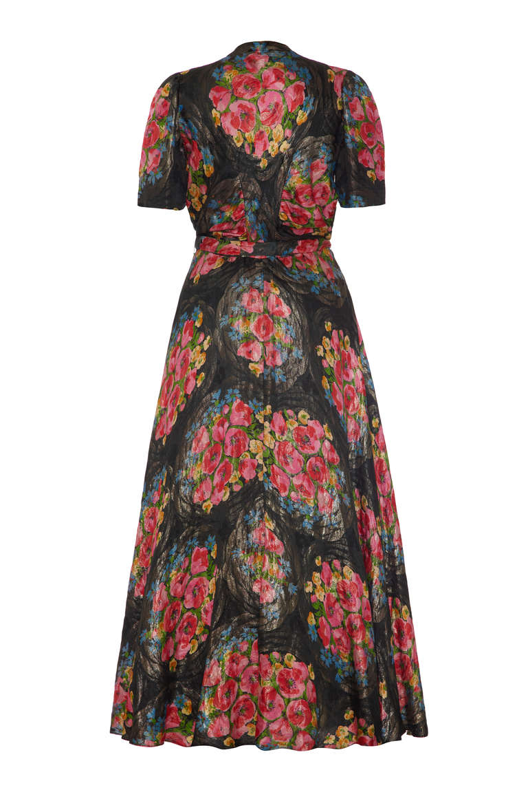 A real show stopper! This is an amazing full-length lame dress in black and gold with an unusual and bold swirling pink and yellow floral print.  It features puff sleeves, tiny covered buttons to fasten up the front and comes with a matching belt to