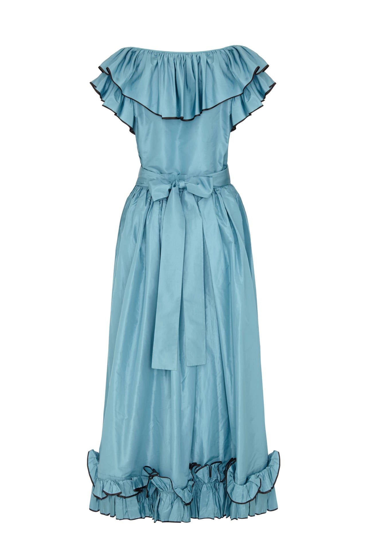 Mid 1970s blue taffeta skirt and top set with ruffle edging by Yves Saint Laurent.  This set comes with matching tie belt and features a bow to the front of the top.  All ruffles are edged with black and the skirt fastens at the side with a zip. 