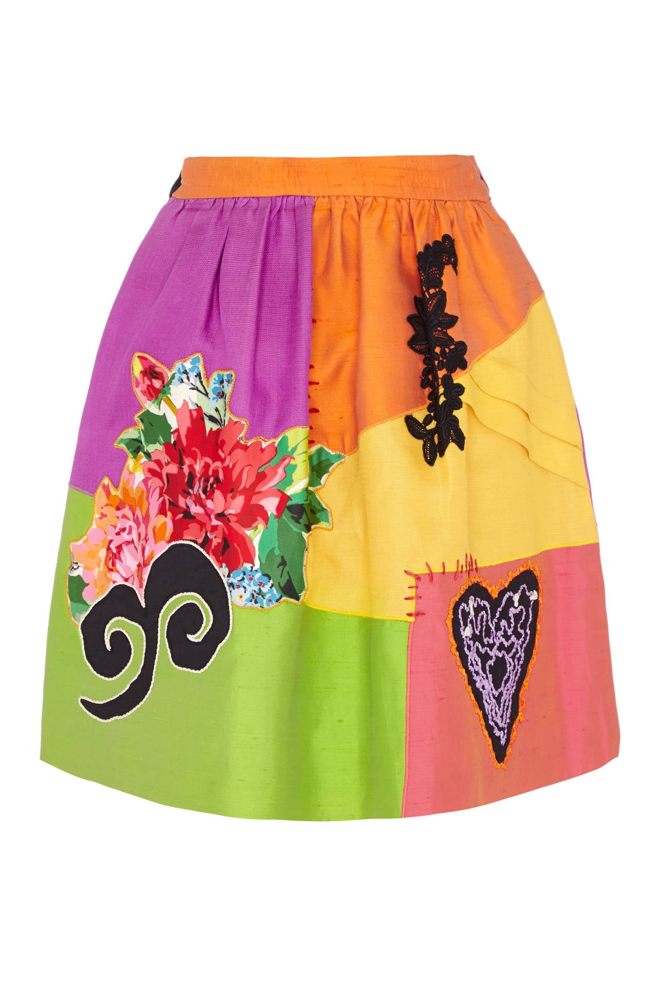 Bright and bold silk knee length skirt from iconic 1990s label Christian Lacroix.  This piece features a patchwork effect with large floral and black appliques. It is fully lined in an orange silk lining, fastens at the side with a zip and has an