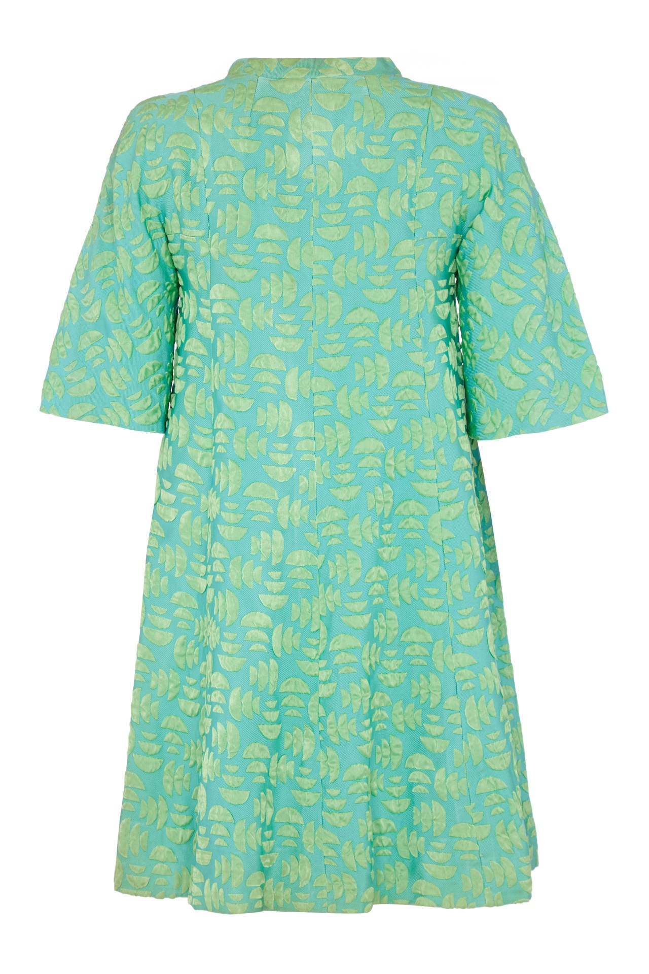 Stunning Jean Muir turquoise A-line shift dress with a lovely miniature semicircle jacquard silk pattern and covered buttons to fasten down the front. So typical of the style of the day this piece features elbow length sleeves, two hip level pocket