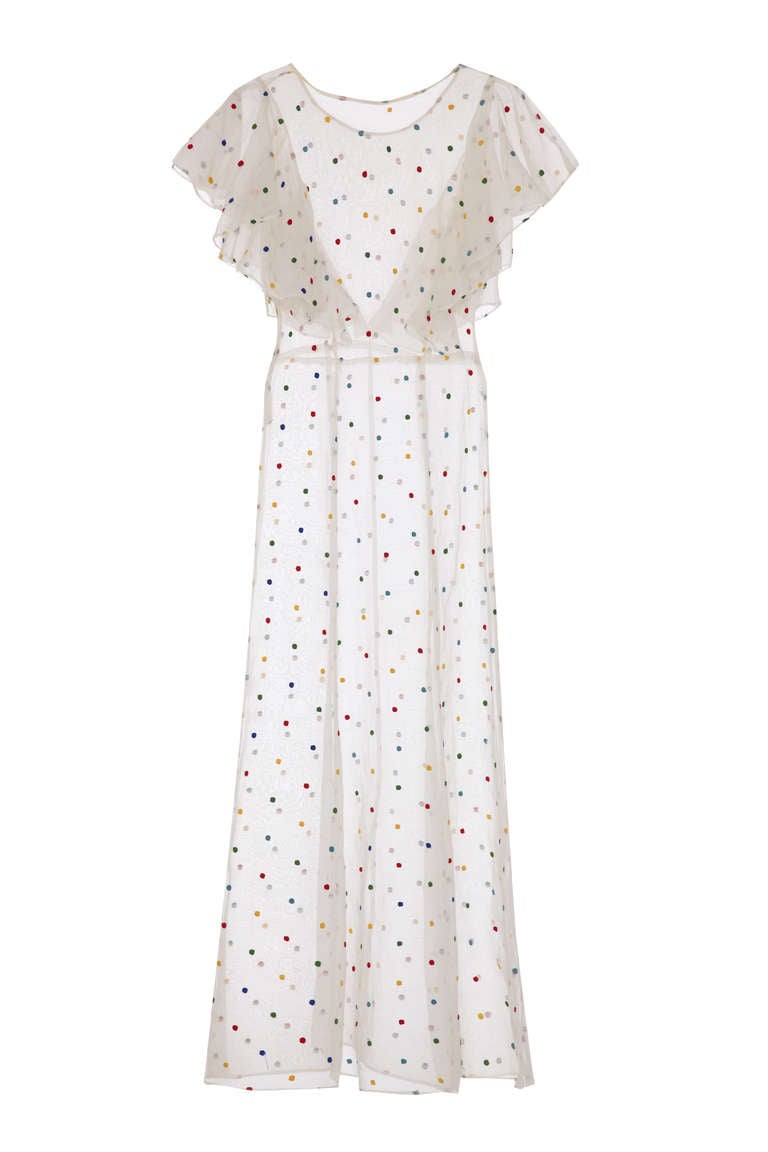 Amazing sheer white organza lawn dress covered in red, blue, yellow and green hand embroidered polka dots. This classic 1930’s dress is full length and sleeveless with oversized ruffles from front to back acting as a small cap sleeve. A fabulous