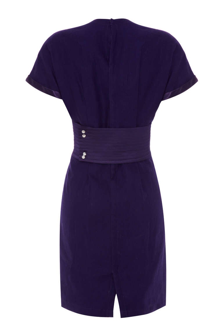 An early piece from Gianni Versace this 80’s purple linen dress is super stylish and easy to wear.  Featuring a wide half belt to the back, which fastens off centre with four pretty buttons and satin trim around the edge of the sleeves and breast