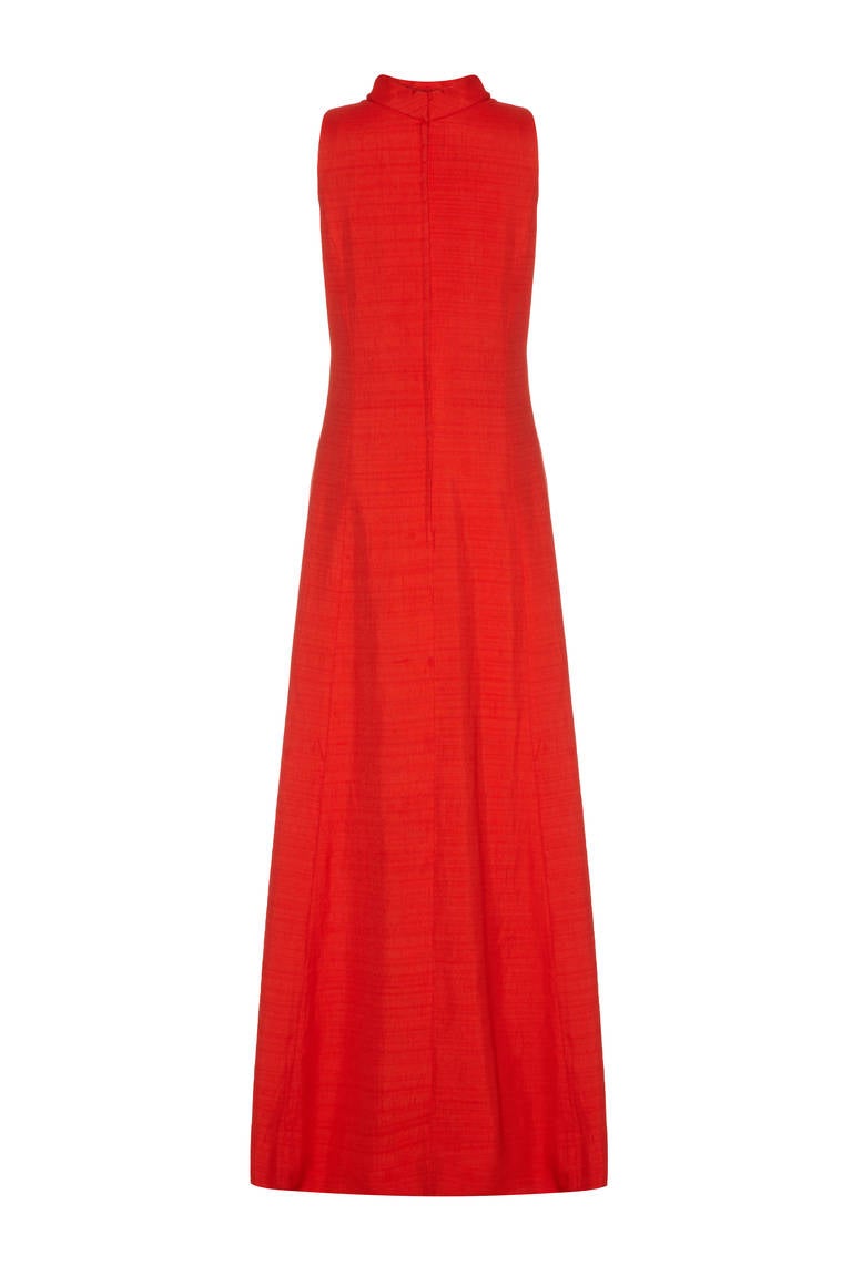 A stunning full length dress from Mr Blackwell, typical of the style of the day and complete with its original tags meaning it has never been worn!  This simple yet elegant piece is 100% silk and a striking orange/ coral colour.  It features two