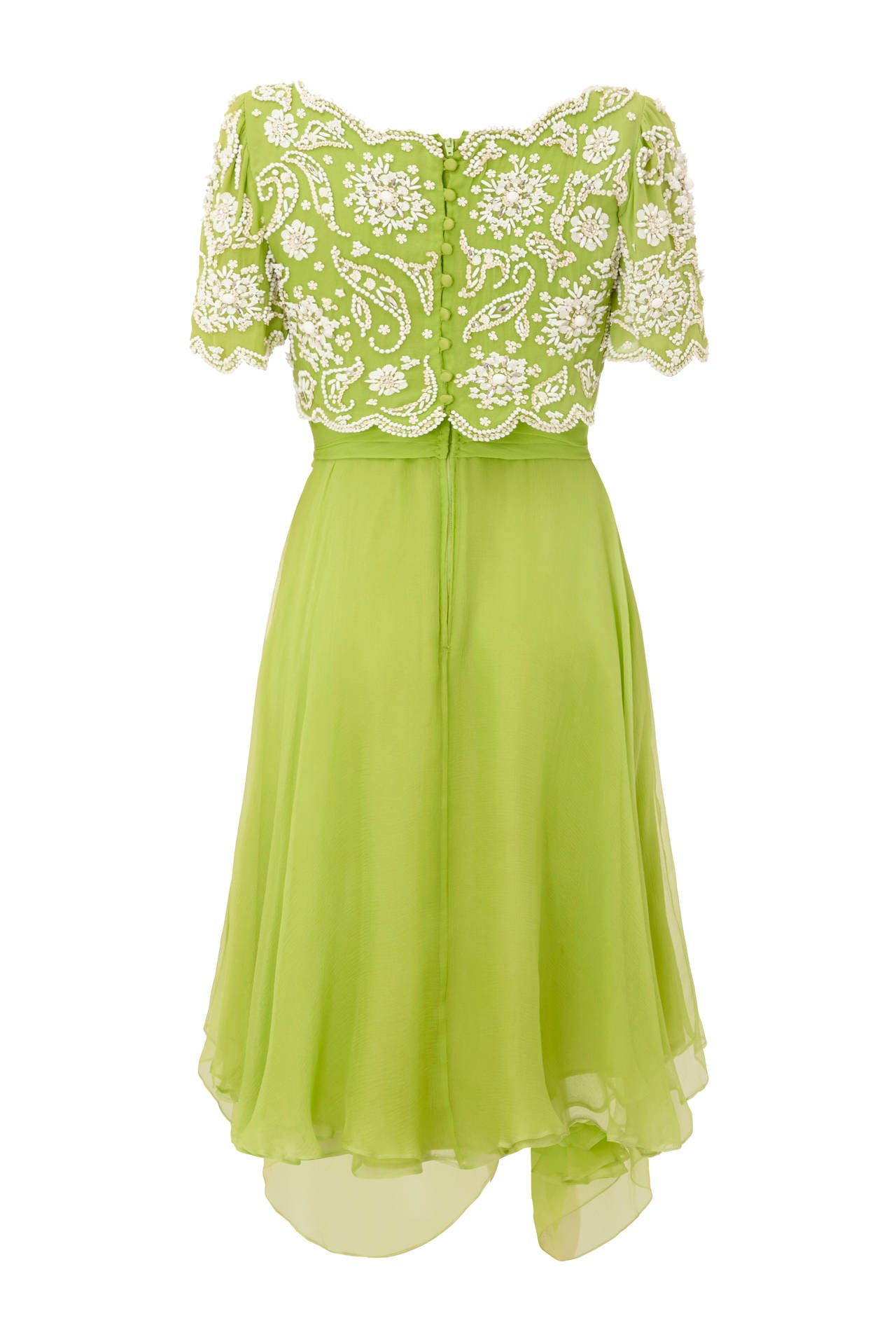 Gorgeous lime green silk chiffon layered dress with white beads and sequins in an intricate pattern on a scalloped edged bodice.  This stunning piece from British designer Ian Thomas, who famously designed for The Queen, features a draped skirt,