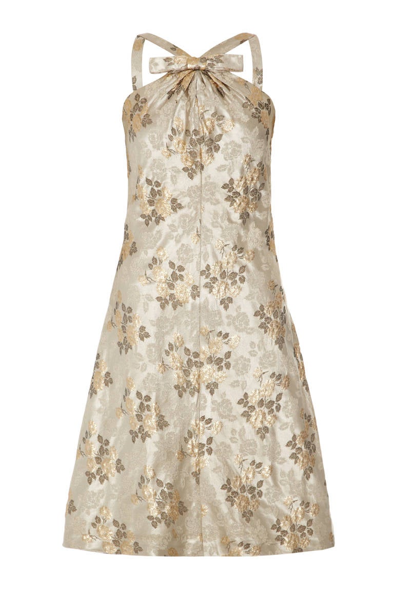 Gorgeous French couture dress and jacket suit in a beautiful gold tone floral brocade.  The A line dress features a cute bow and gathering detail at the front with the straps extending form the middle and fastens at the back with a zip.  The jacket