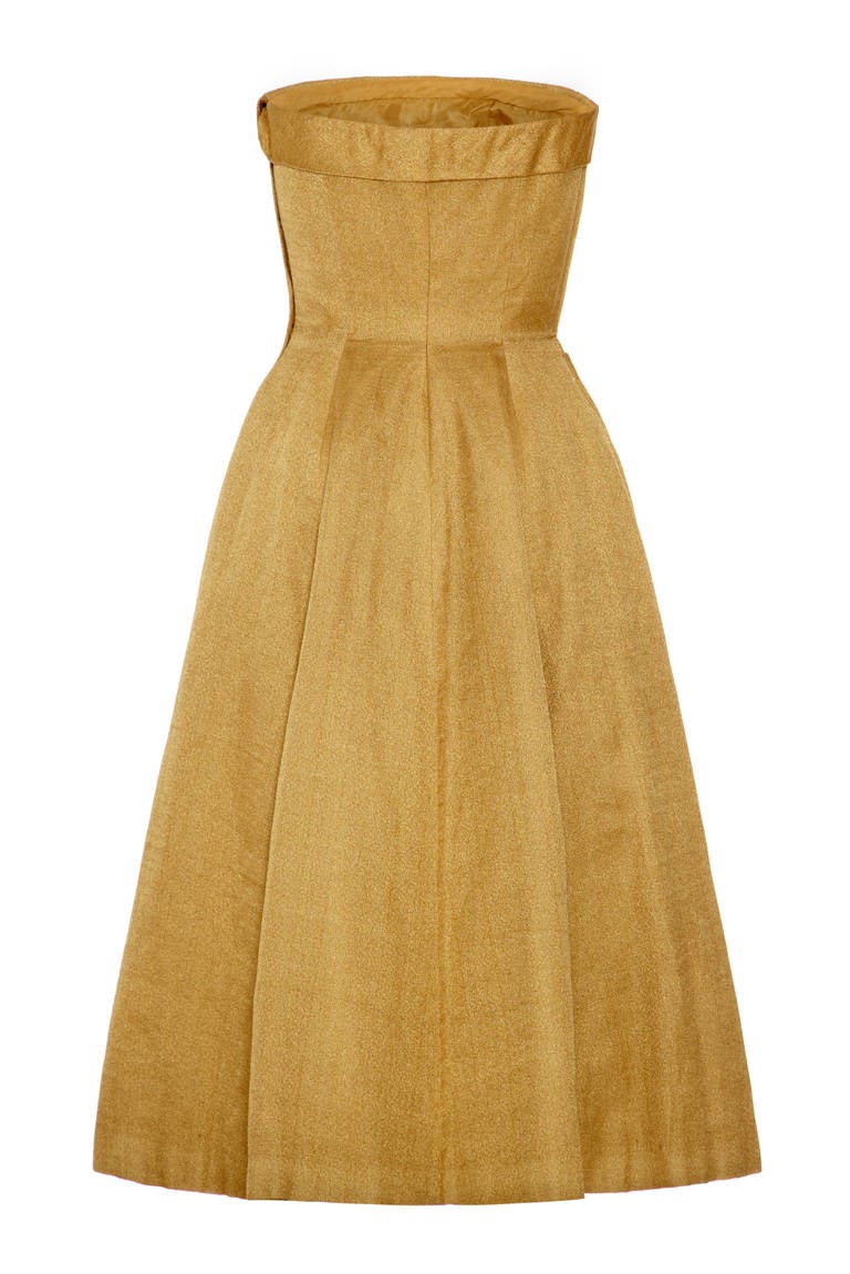 Amazing 1950s strapless dress in a beautiful textured woven gold fabric.  This couture made piece features a full calf length skirt and some lovely detailing with decorative covered buttons down the centre front and a large asymmetrical bow to the
