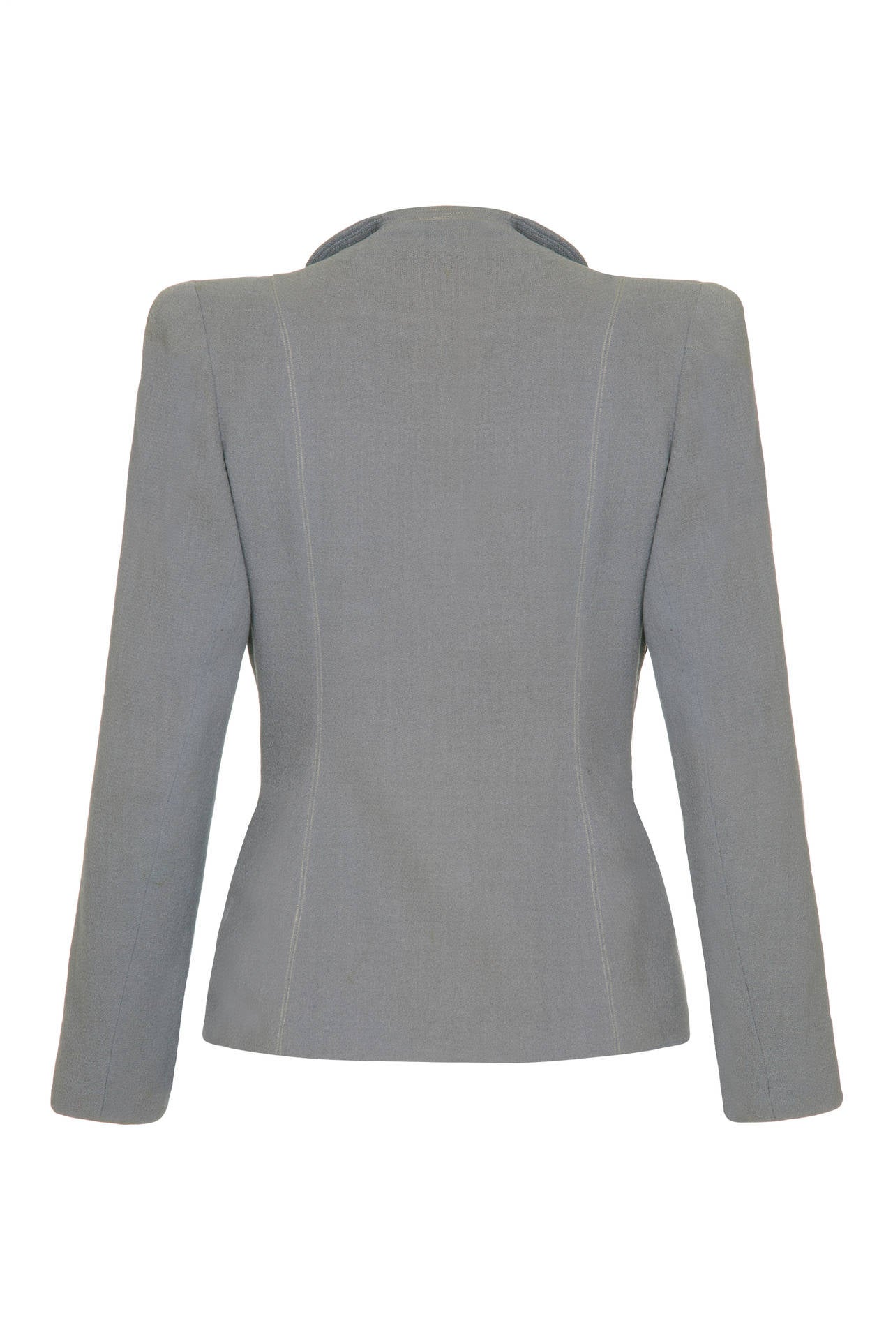 Beautiful soft tailored jacket in dove grey with lovely, classic deco details.  It is fully lined in a coordinating silk lining and features shoulder pads, arrow shaped pockets and topstitching throughout.  It fastens at the waist with a hook and