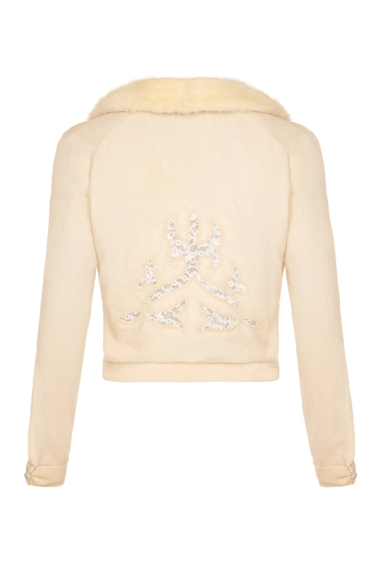 Beautiful soft cream cashmere cardigan featuring lovely cut out details backed in lace with embroidered edging. The mink collar is completely detachable and fastens to the cardigan with poppers. It fastens at the front with hooks and eyes and a