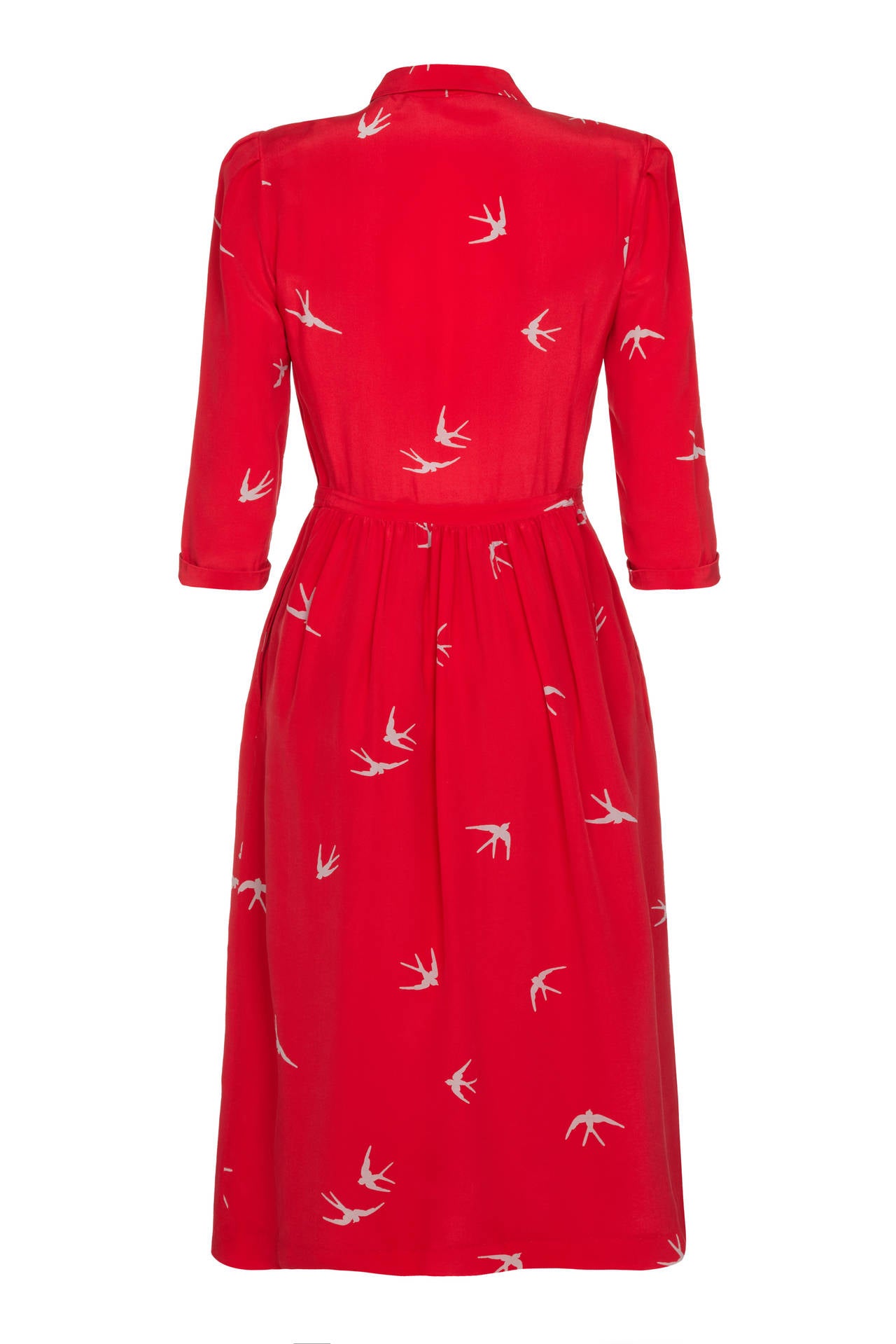 Great 70s shirt dress by Cacharel in red silk with a pretty grey bird print. It features ¾ length sleeves, ivory buttons to fasten at the front and matching original belt.  There are two pockets to the hip of the below the knee skirt and it is