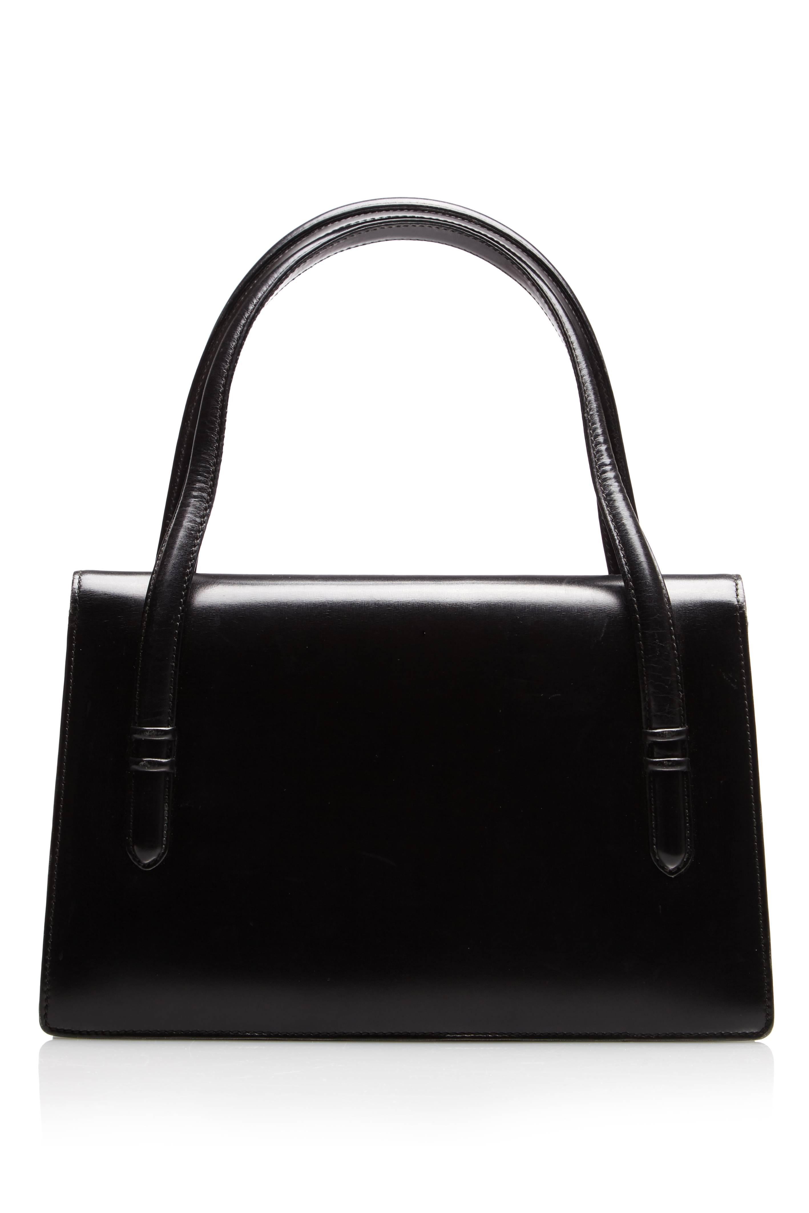 Vintage 1960s black leather handbag by Gucci. This piece has two strap handles,  a gold flip closure and comes with a dust bag. Inside there are two main compartments with a further two pockets inside the back compartment, one with a zip to fasten.