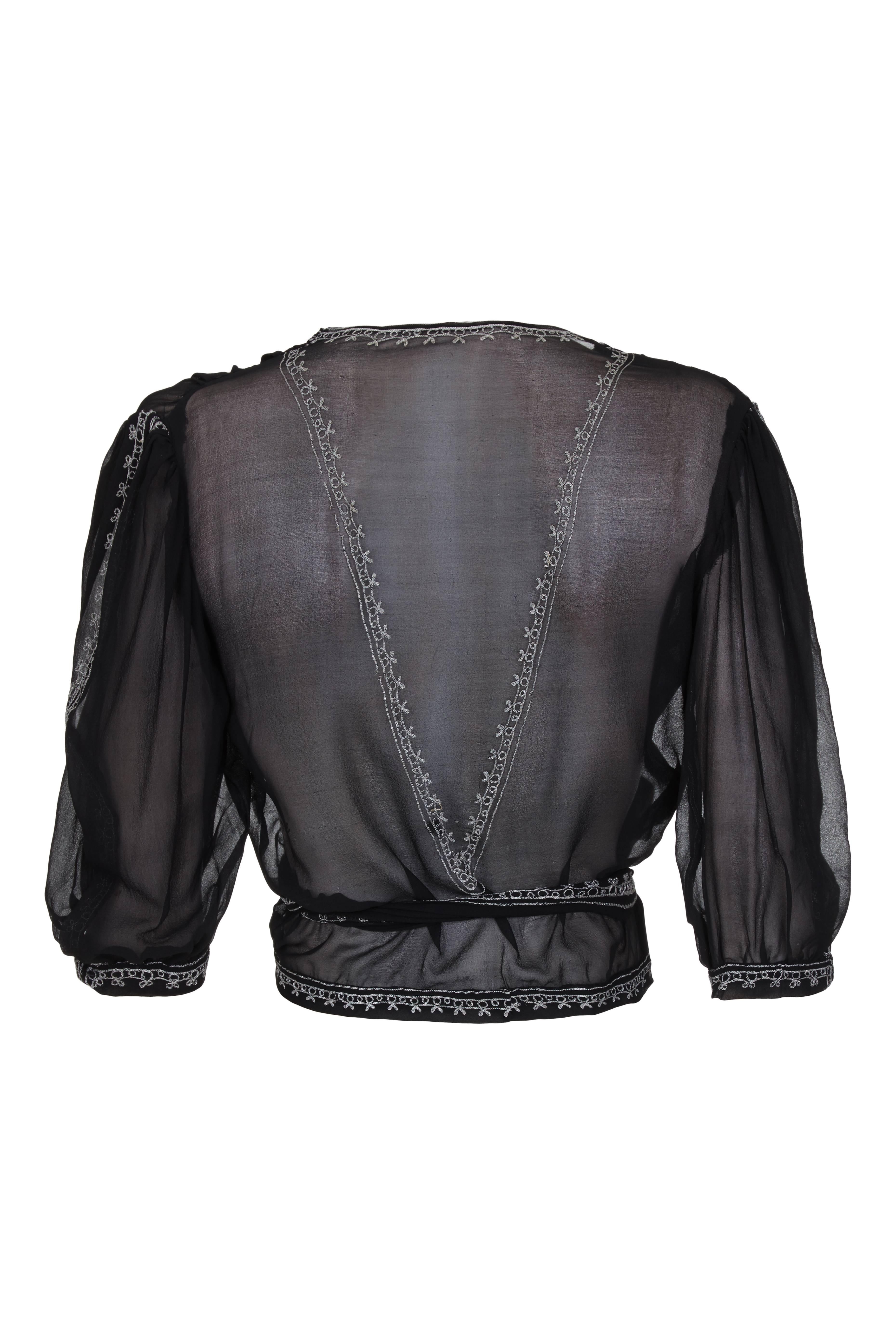 Beautiful vintage 1930s black chiffon blouse with cross over front and tie fastening to one side.  This simple yet elegant piece features pretty chain stitched silverembroidery around all the edges and in a V on the back. Some of the embroidery has