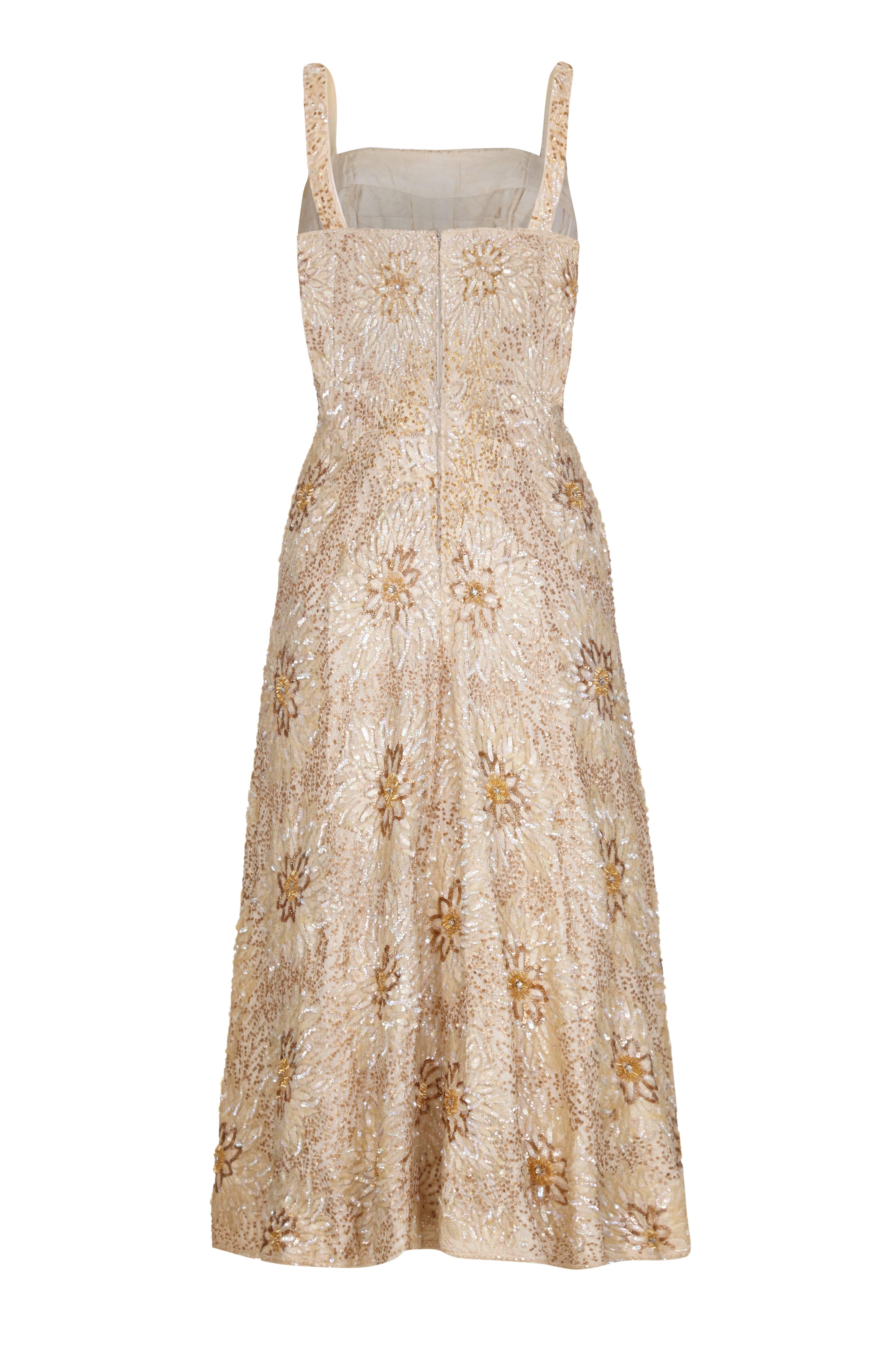 Gorgeous vintage 1950s party/ cocktail dress from Pouponne Couture of Monte Carlo.  This lovely hand beaded, couture piece is fully sequined and beaded in large floral motifs in tones of gold and cream. It features thin straps, a boned bodice with