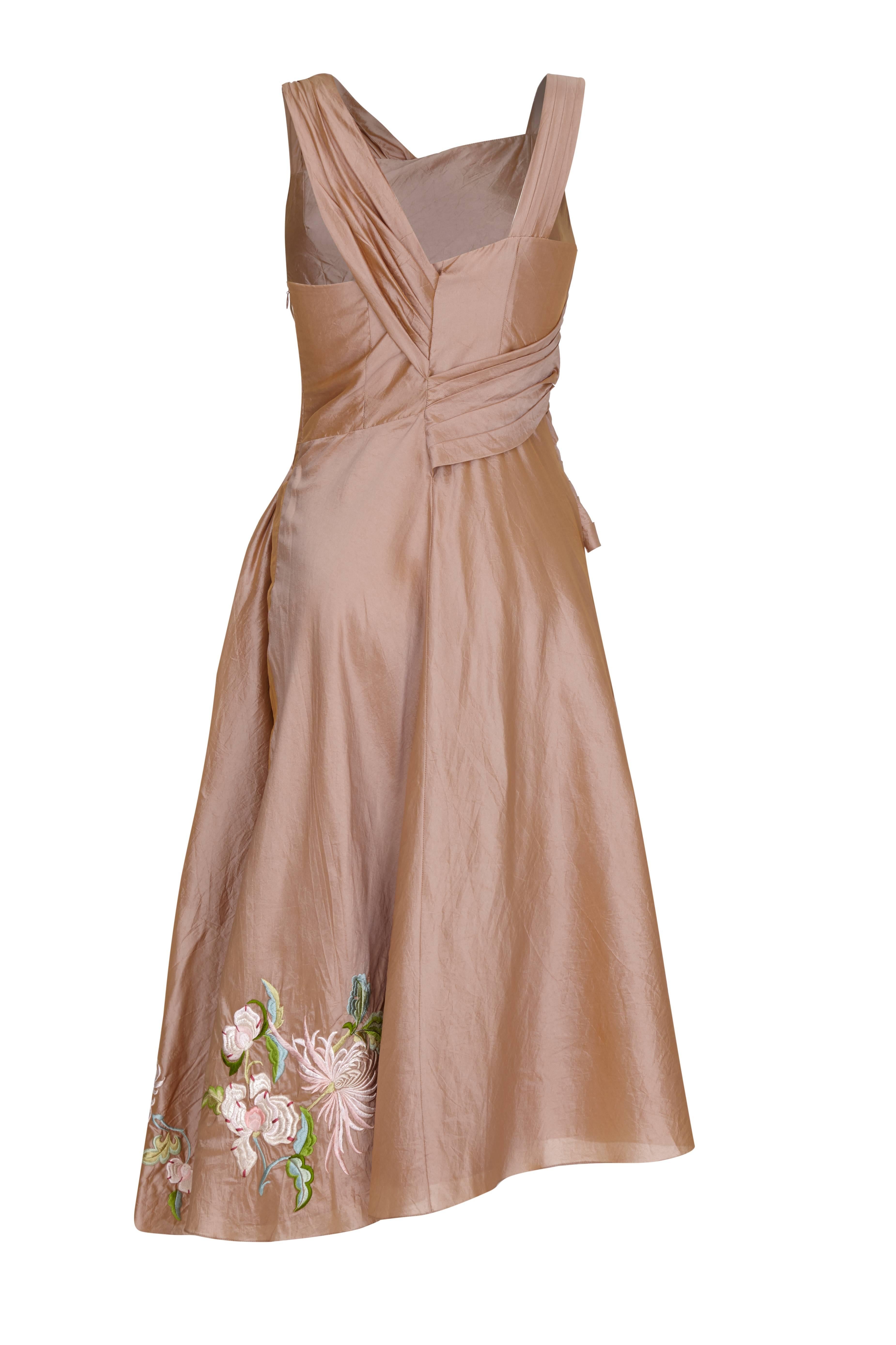 Beautiful 1997 floral embroidered, metallic champagne silk dress by John Galliano for Christian Dior.  This asymmetrical piece features a full skirt, pleated sash detail and fastens at the side with a zip. Inside it is lined in the same champagne