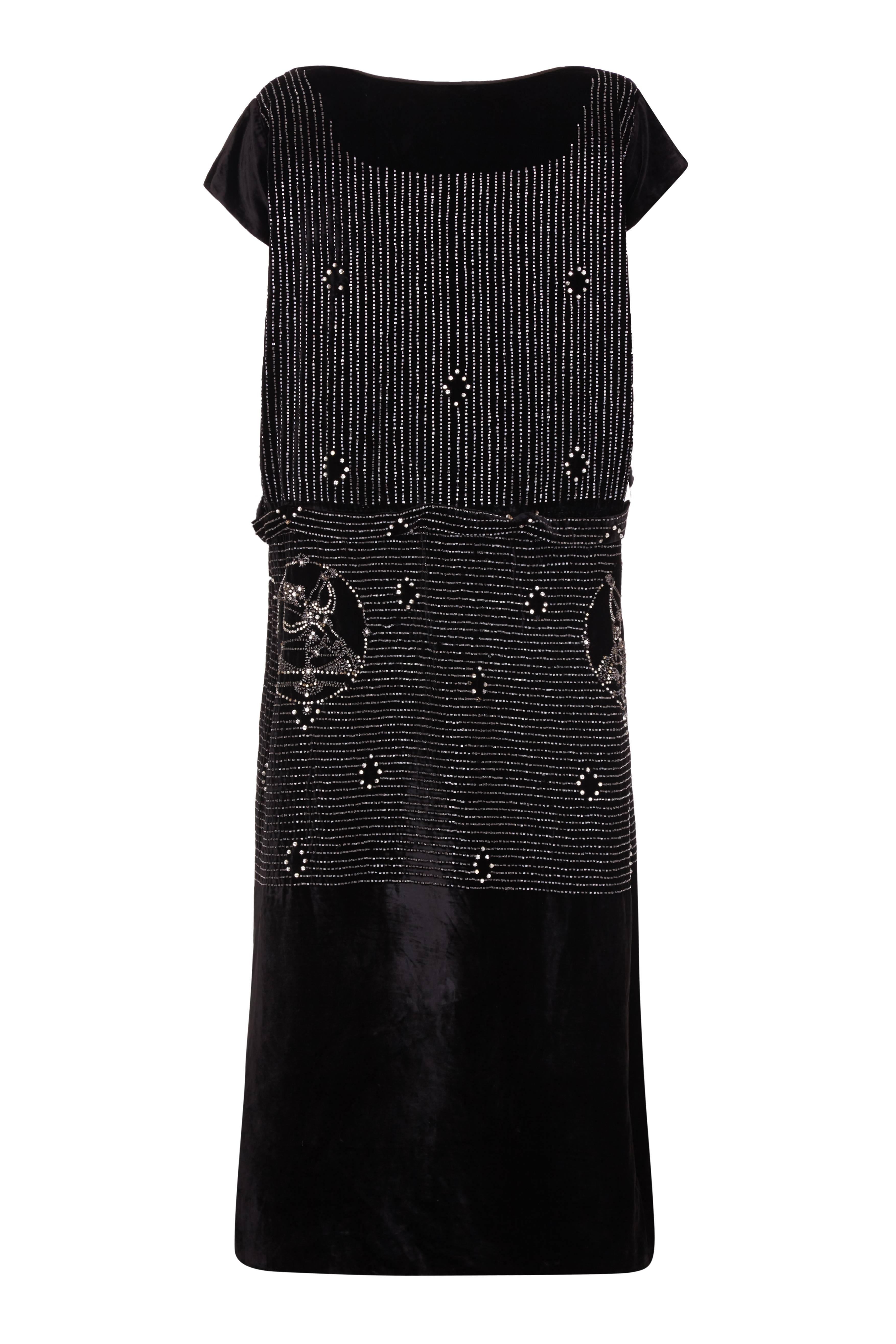 Amazing black silk velvet vintage flapper dress with small bugle beaded rows and dancer motifs.  The dress features an attached original belt, cap sleeves and is straight cut in classic flapper style.  There is a Californian label, Mary Millerick,