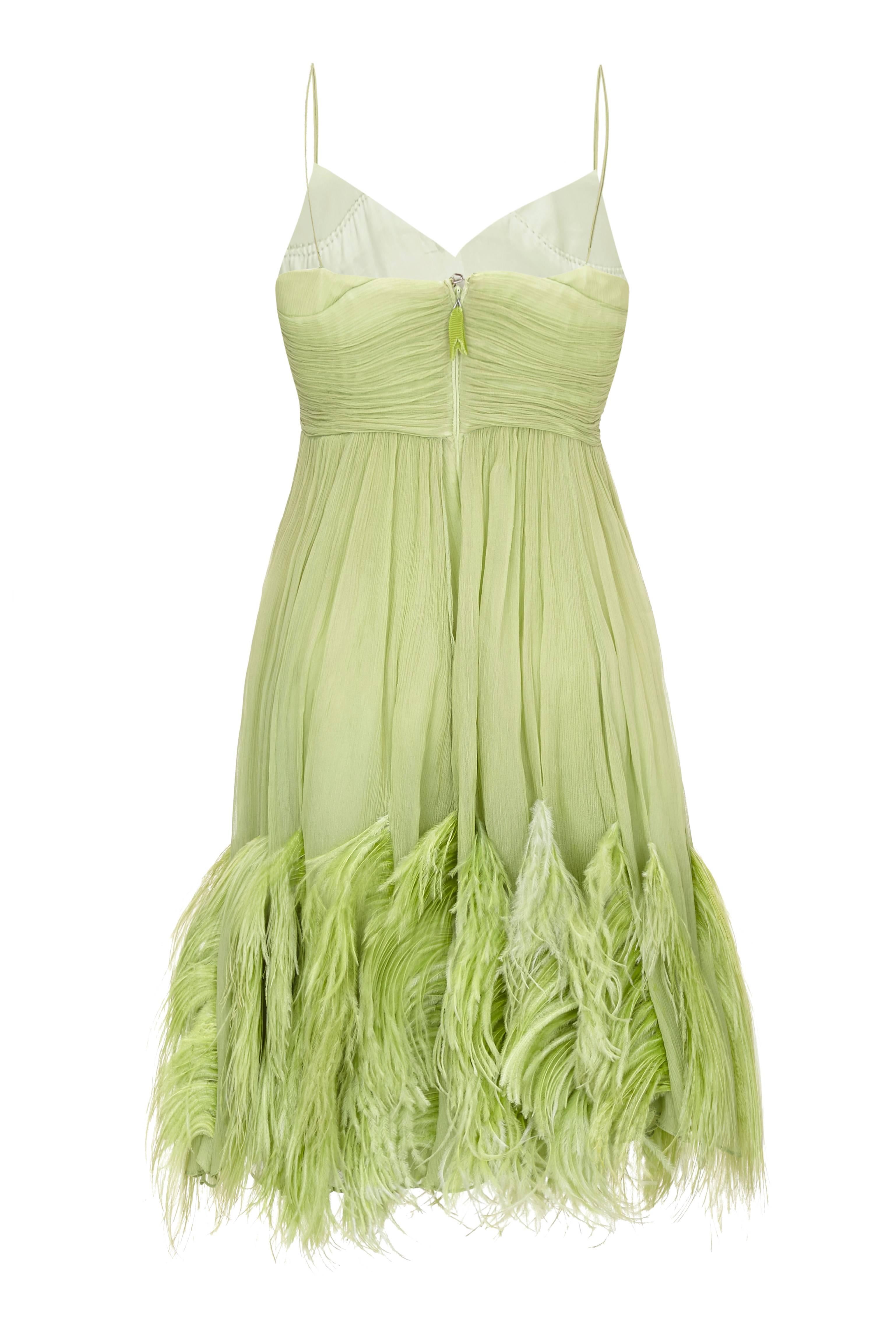 Amazing vintage 1960s mini dress in soft green silk chiffon with fabulous feather trim around the hem. This pretty cocktail dress has ruching around the bust, which finishes at an empire line and a double layered chiffon skirt. It fastens at the