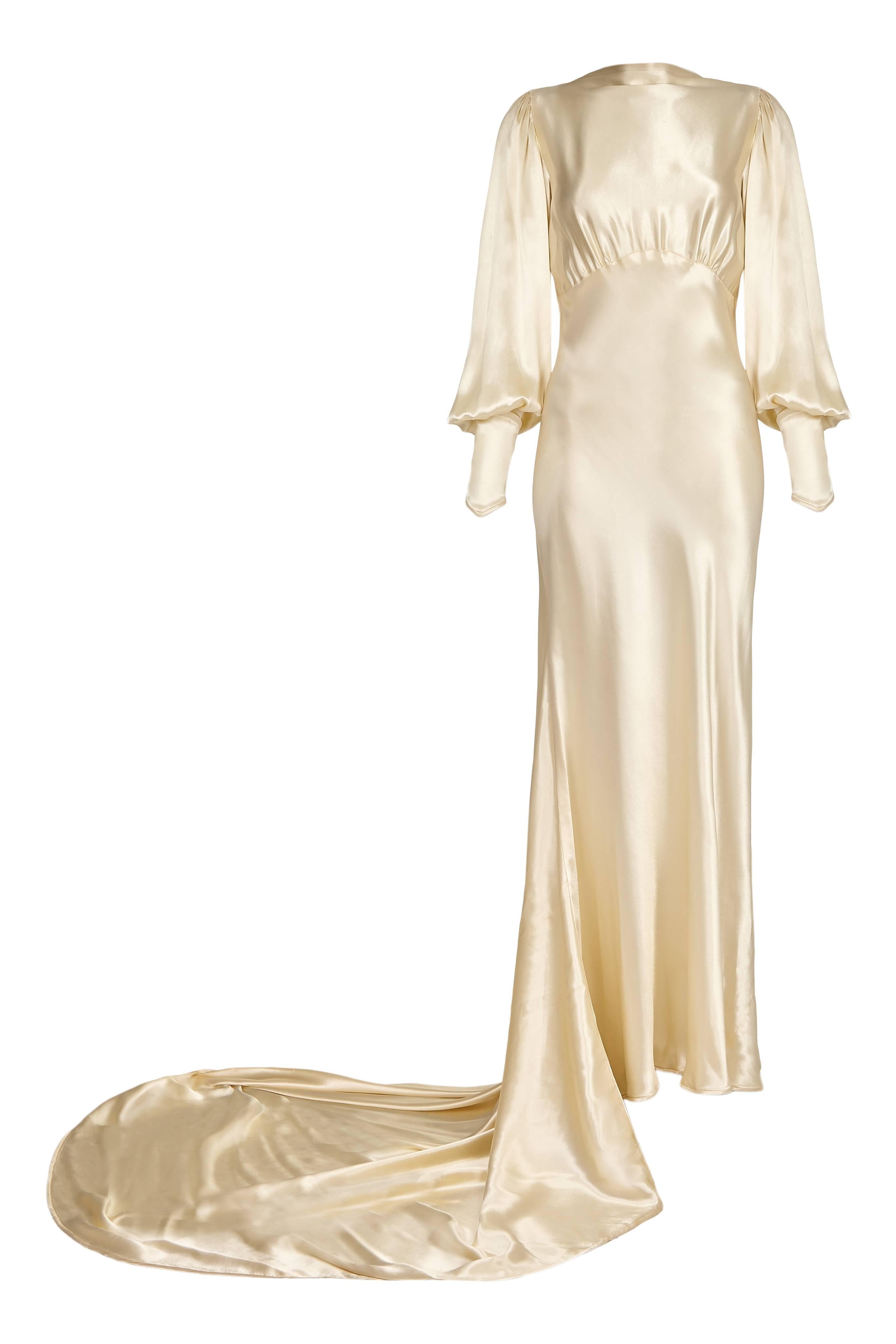Extraordinary vintage 1930s wedding dress in soft ivory silk satin with high neck, open back and cuffed balloon sleeves. This is an extremely elegant gown with a long train and cut on the bias making it very flattering and also flexible in size. 