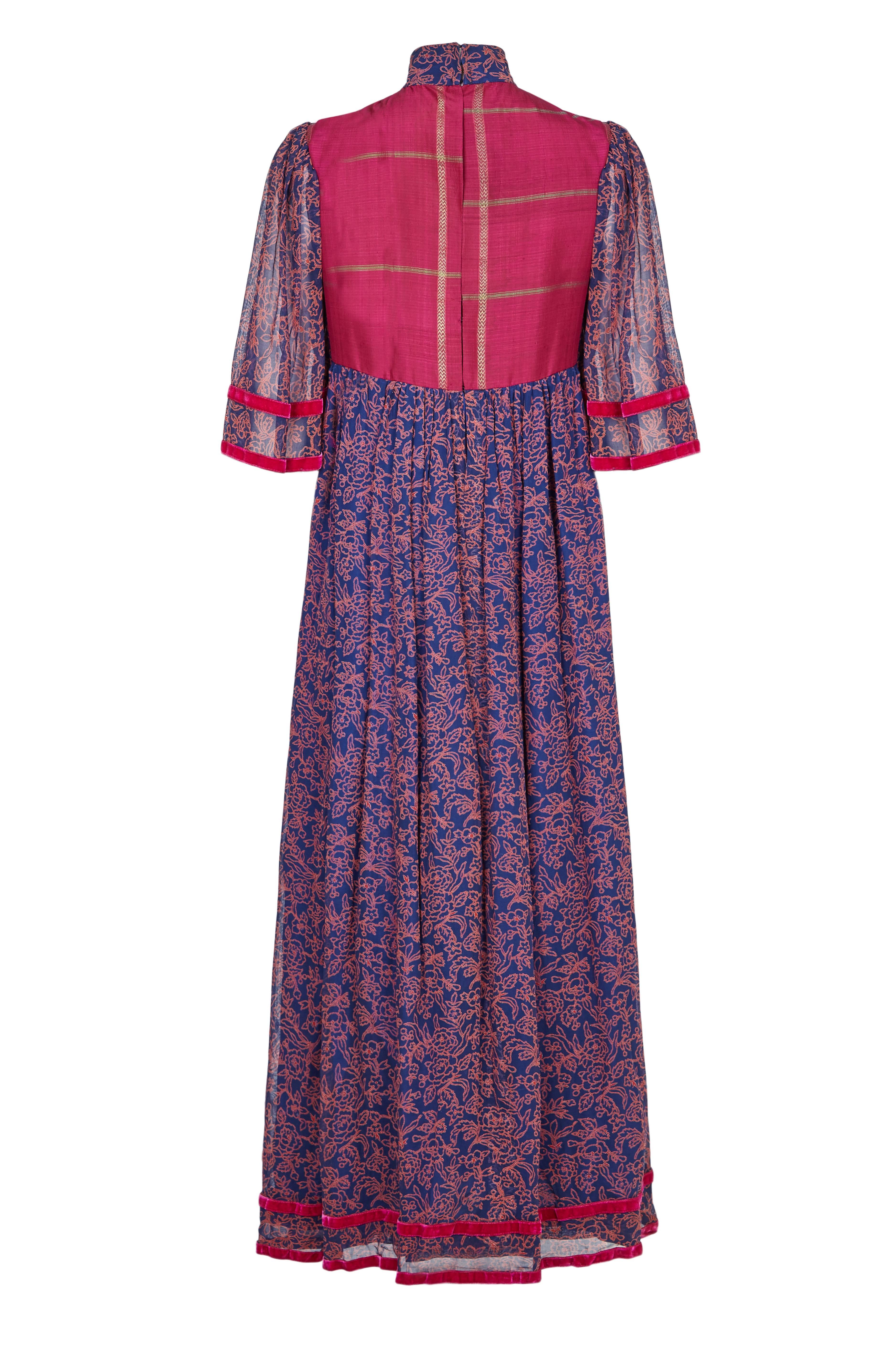 A gorgeous example of the Thea Porter ‘Faye’ dress dating between 1968 and 1970.  This piece is made in a printed deep purple and pink georgette with dainty floral pattern.  It has a pink velvet trim around the wide flowing sleeves and hem, and an