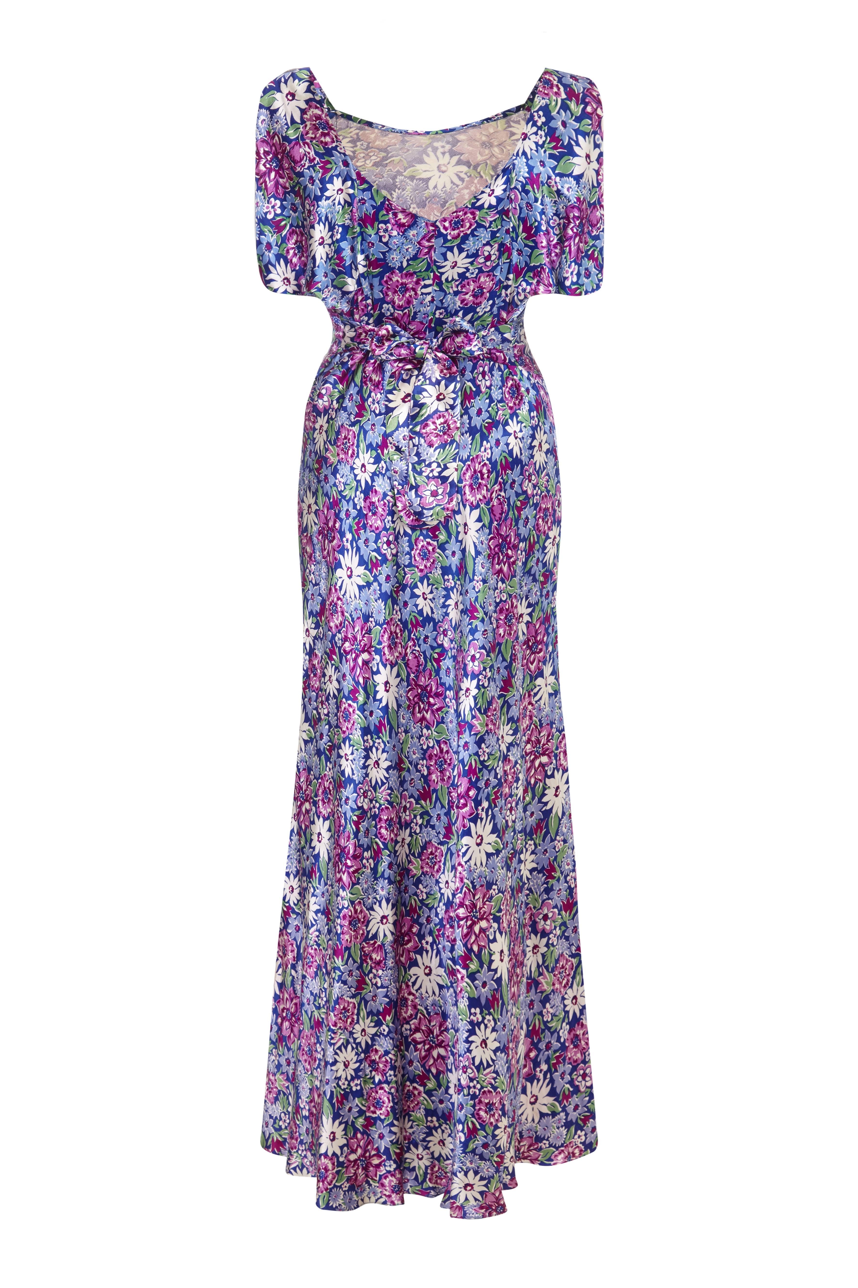 Amazing vintage 1930s bias cut satin full length dress with lovely purple and white floral print. This dress is full of character with lovely art deco details, it has sunburst pleats at the bust and draped sleeves typically of the style of the day. 