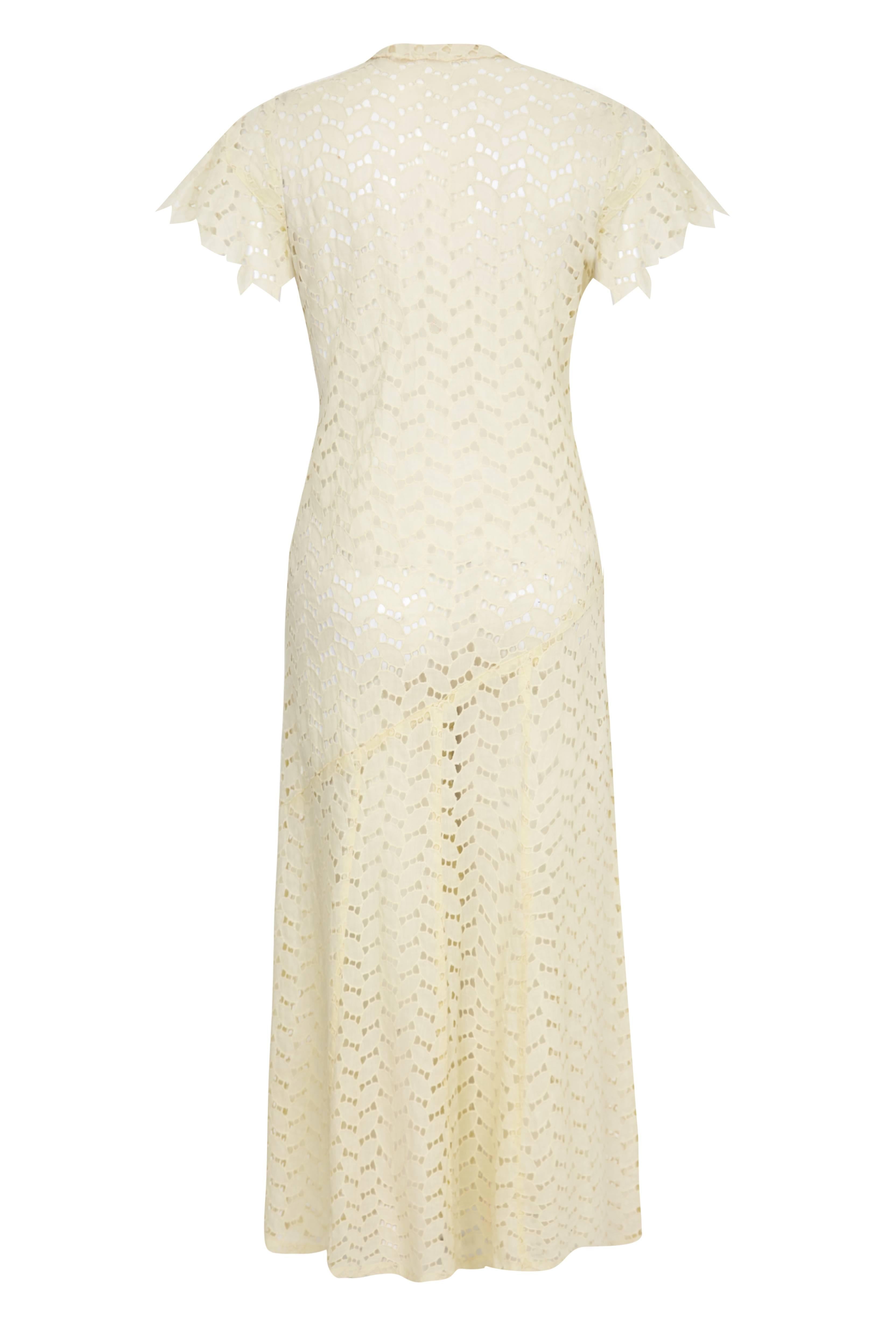 Lovely vintage 1920s buttermilk fine cotton dress with intricate cut work in leaf shapes. This dress is in the typical ‘flapper’ style with no waist shaping. It has an asymmetrical hip seam, panelled skirt and cross over front with lapels. It is in