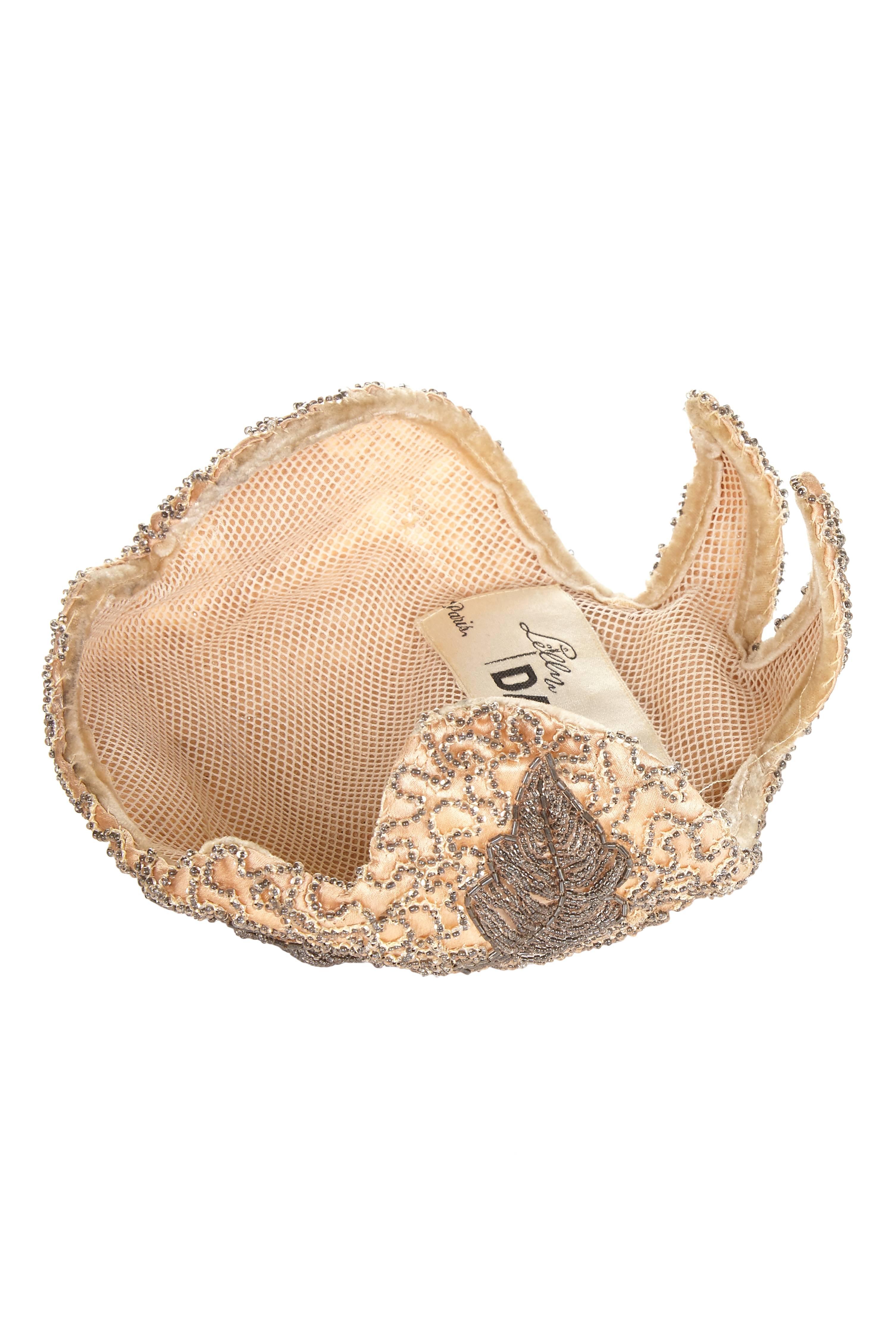 Beautiful vintage 1950s cocktail hat from French milliner Lilly Dache. This exquisite piece features a pale pink silk base with intricate silver beading forming leaf motifs and is in excellent condition with no flaws to mention.