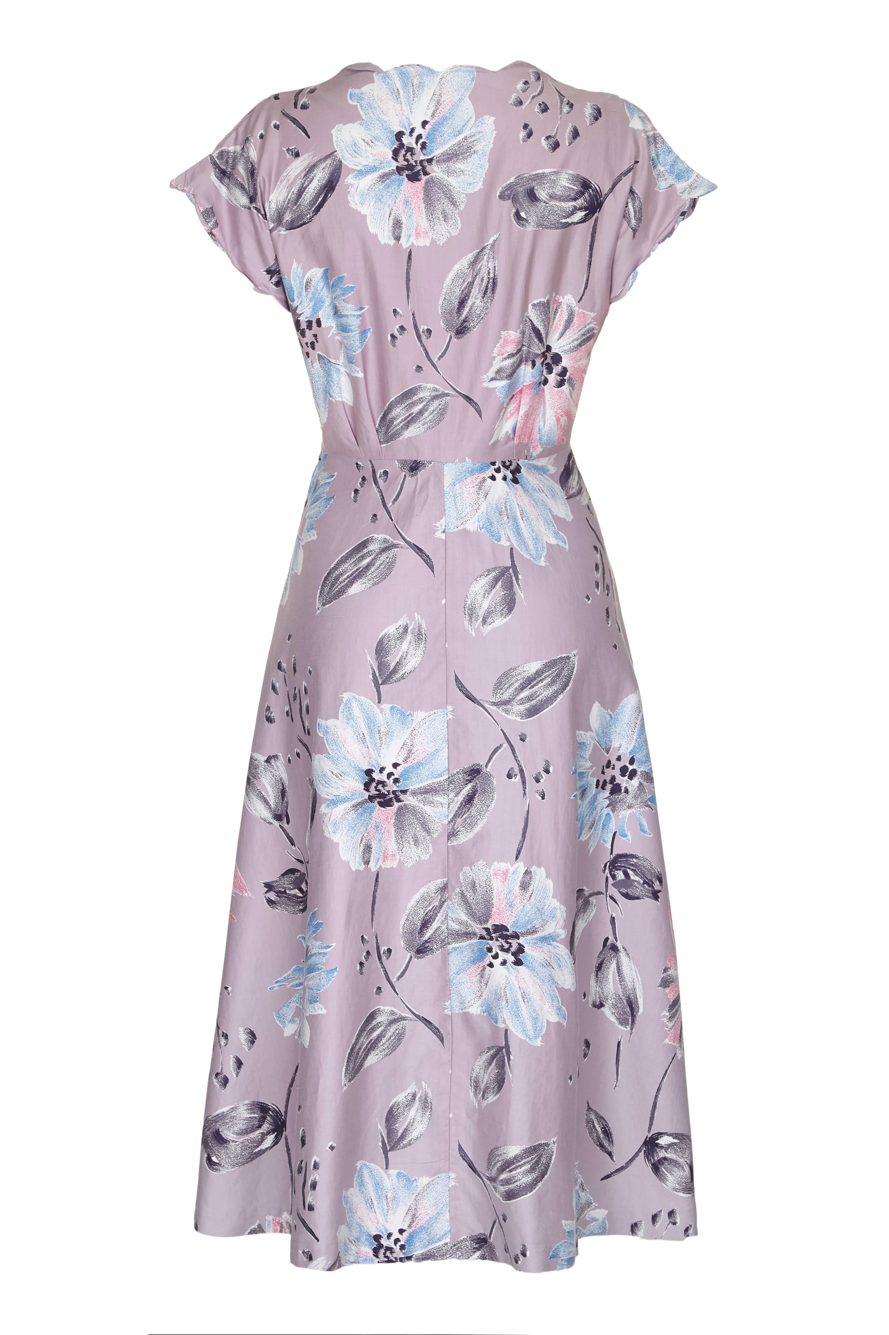 Very pretty unlabelled but professionally made vintage 1950s mauve polished cotton day dress with large floral print.  This dress is classic 50s in style with full skirt, fitted waist and cute scalloped edge detail on the neckline and armholes. It