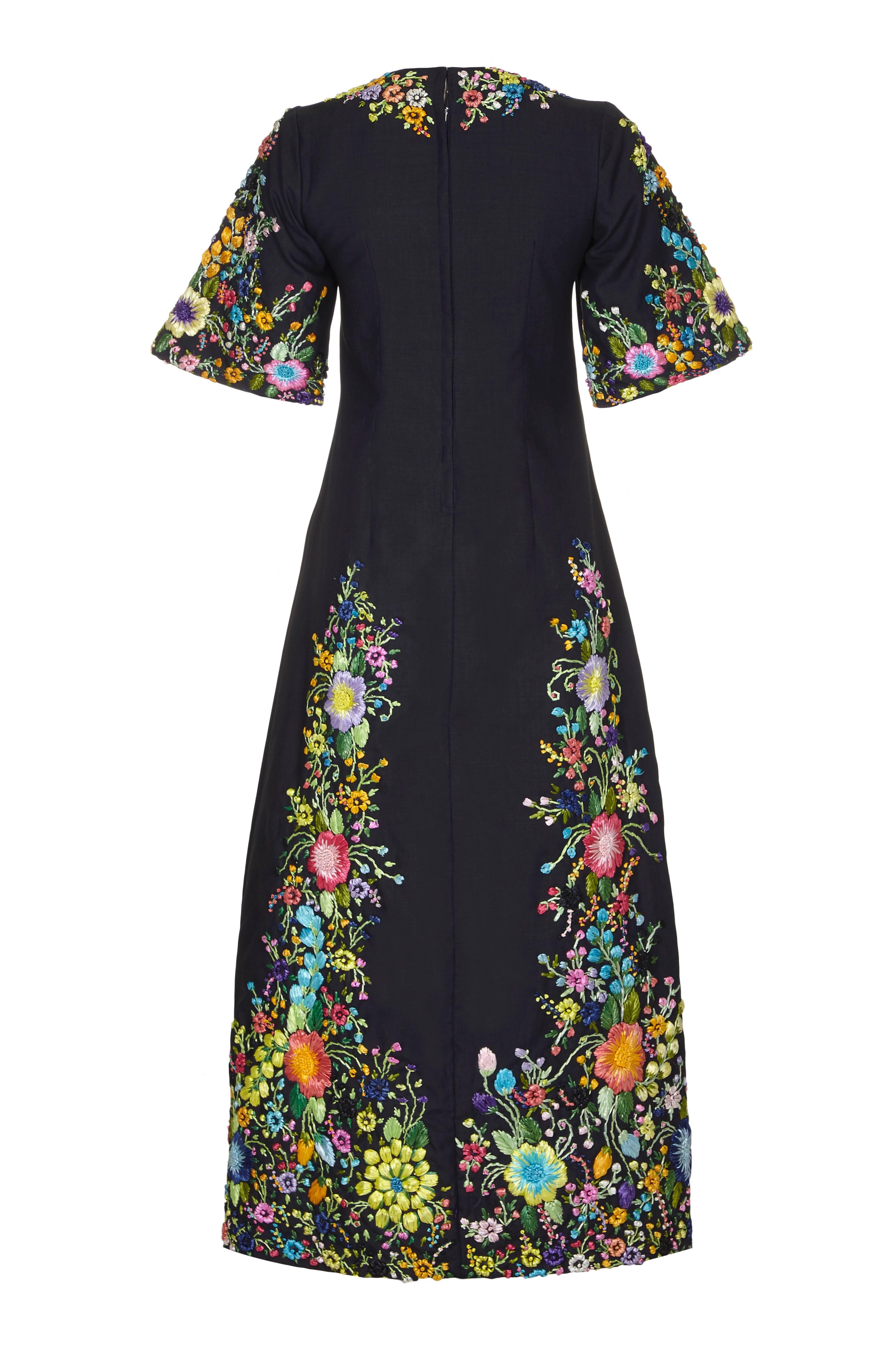 Extraordinary vintage 1960s black linen full-length dress with unbelievable multi coloured floral raffia embroidery. Featuring elbow length flared sleeves and an A-line cut skirt this dress fastens at the back with a zip and is fully lined.  An