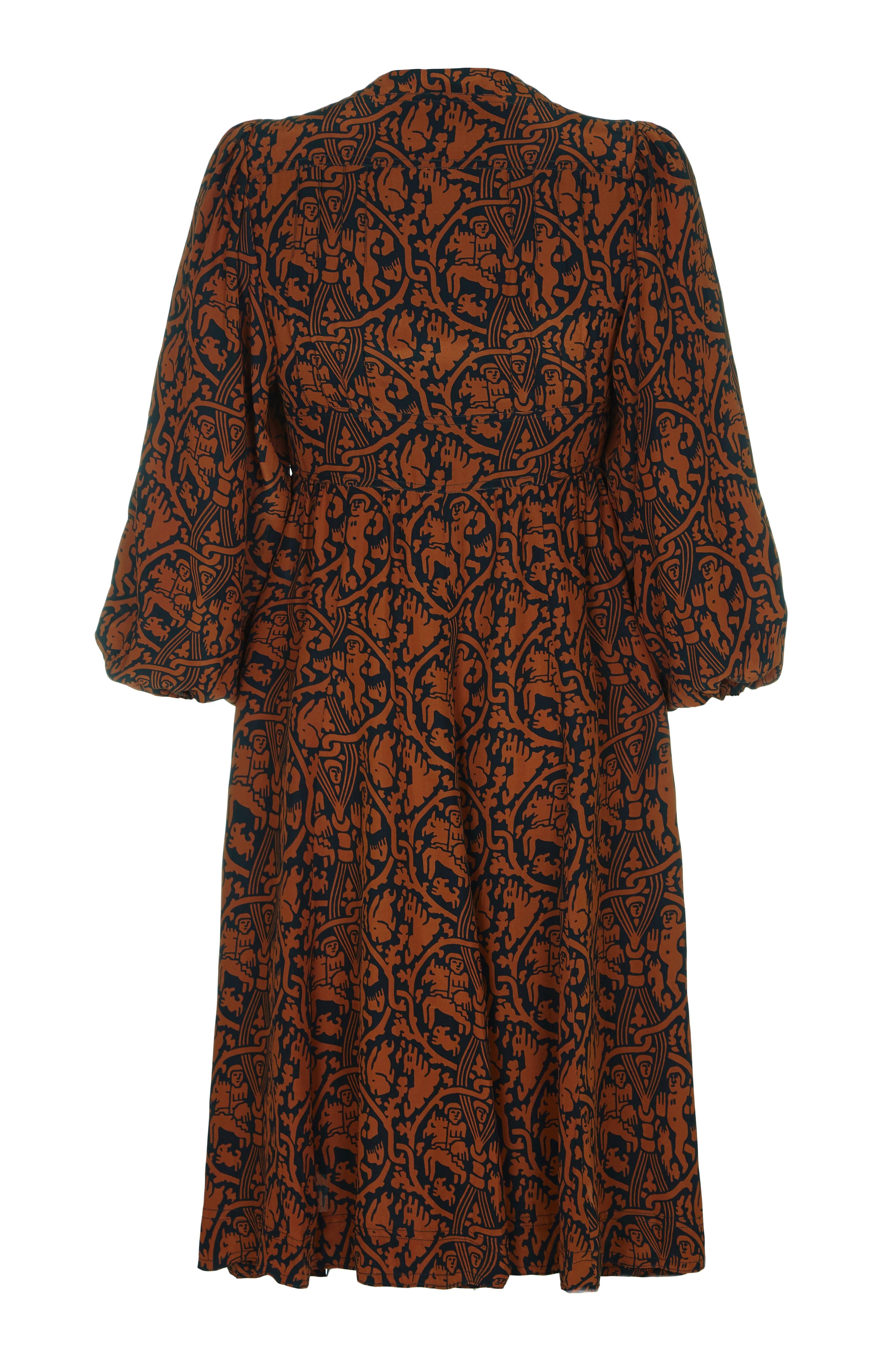 Fantastic vintage 1970s Jean Muir silk dress with novelty ancient civilisation print in terracotta on a black background.  The dress features 3/4 balloon sleeves, A-line skirt and a band under the bust.  It fastens at the front with buttons and is
