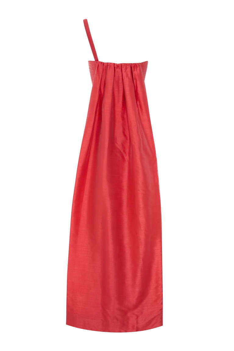 Questo sensazionale abito in seta strutturata degli anni '60, di colore rosa corallo intenso, è opera del celebre stilista Frank Usher. Questo pezzo elegante è caratterizzato da un vistoso strascico a tutta lunghezza al centro della schiena e da un