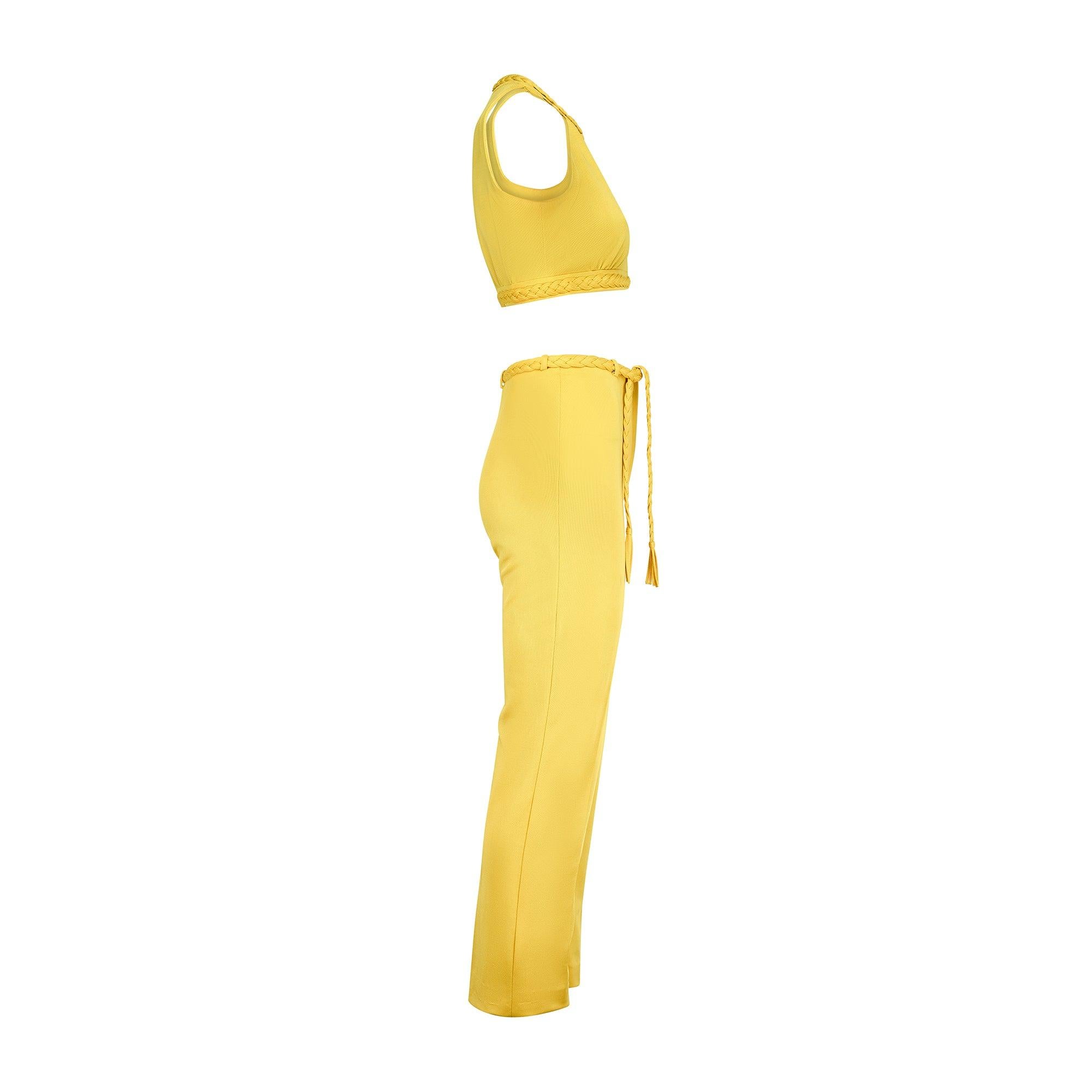 Cet ensemble crop top et pantalon du début des années 1970 par Dana est une pièce de marque de villégiature précoce fabriquée sur la Côte d'Azur française. Confectionné en jersey jaune vif, il est agrémenté d'un tressage épais. Le haut est coupé de