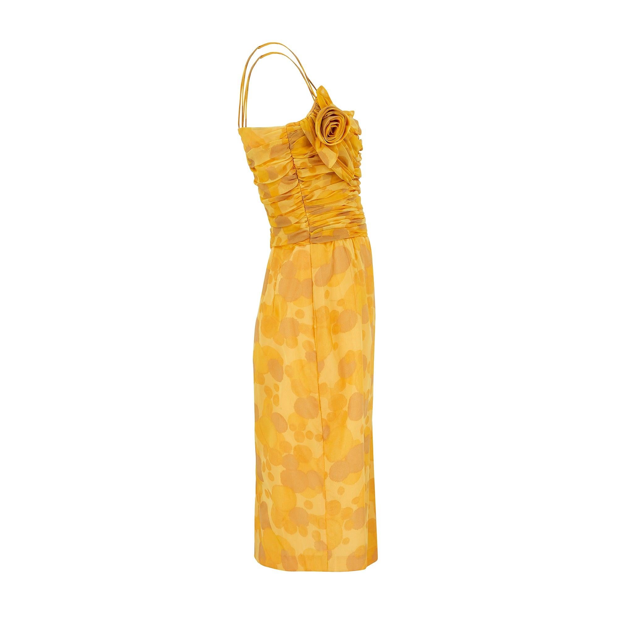 Cette magnifique robe en mousseline de soie jaune soleil des années 1960 a été fabriquée par Lee Delman en Angleterre. Le Label était vendu chez Harrods et faisait partie du gratin du prêt-à-porter britannique dans les années 1950 et 1960. La