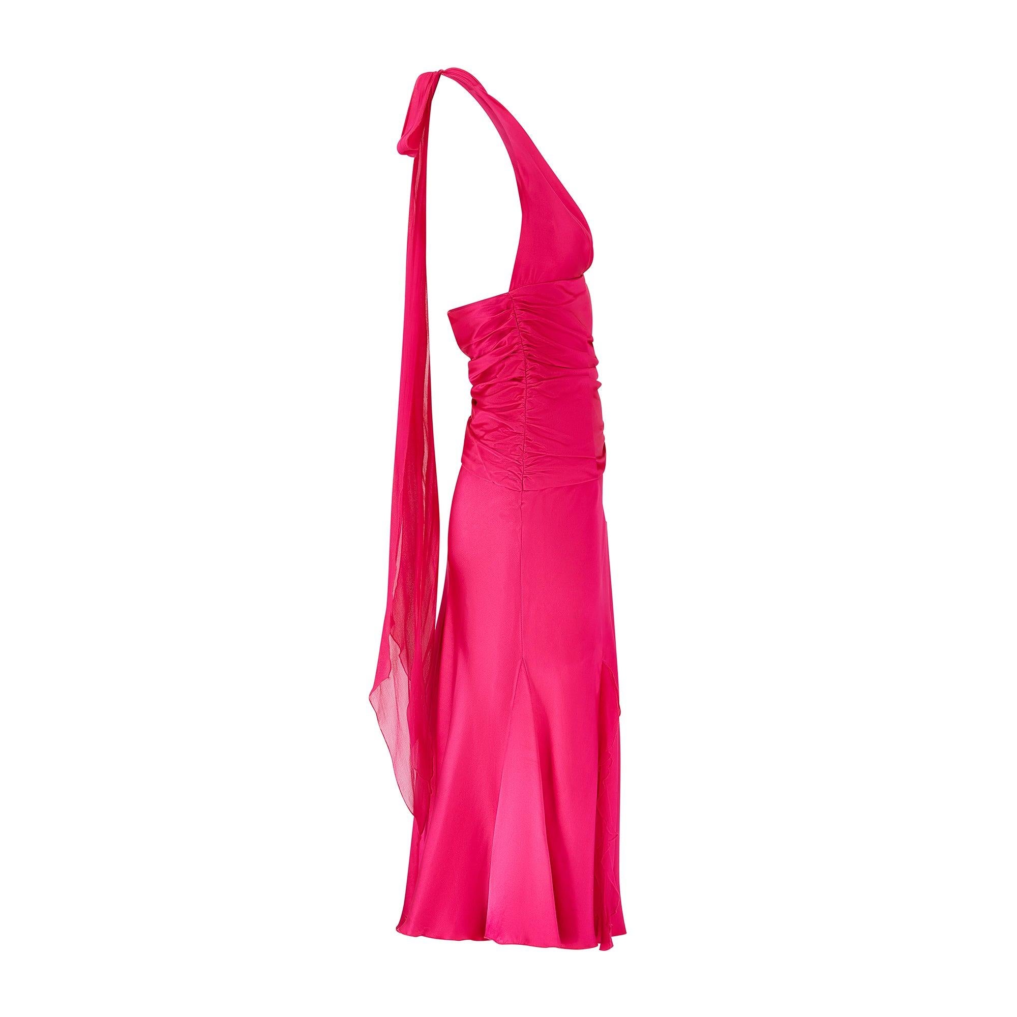 Cette robe de cocktail des années 1990 est confectionnée dans une fabuleuse nuance de satin de soie fuchsia très brillant. Elle présente une encolure licou ludique et un buste légèrement plissé. L'empiècement du corps est froncé à partir des