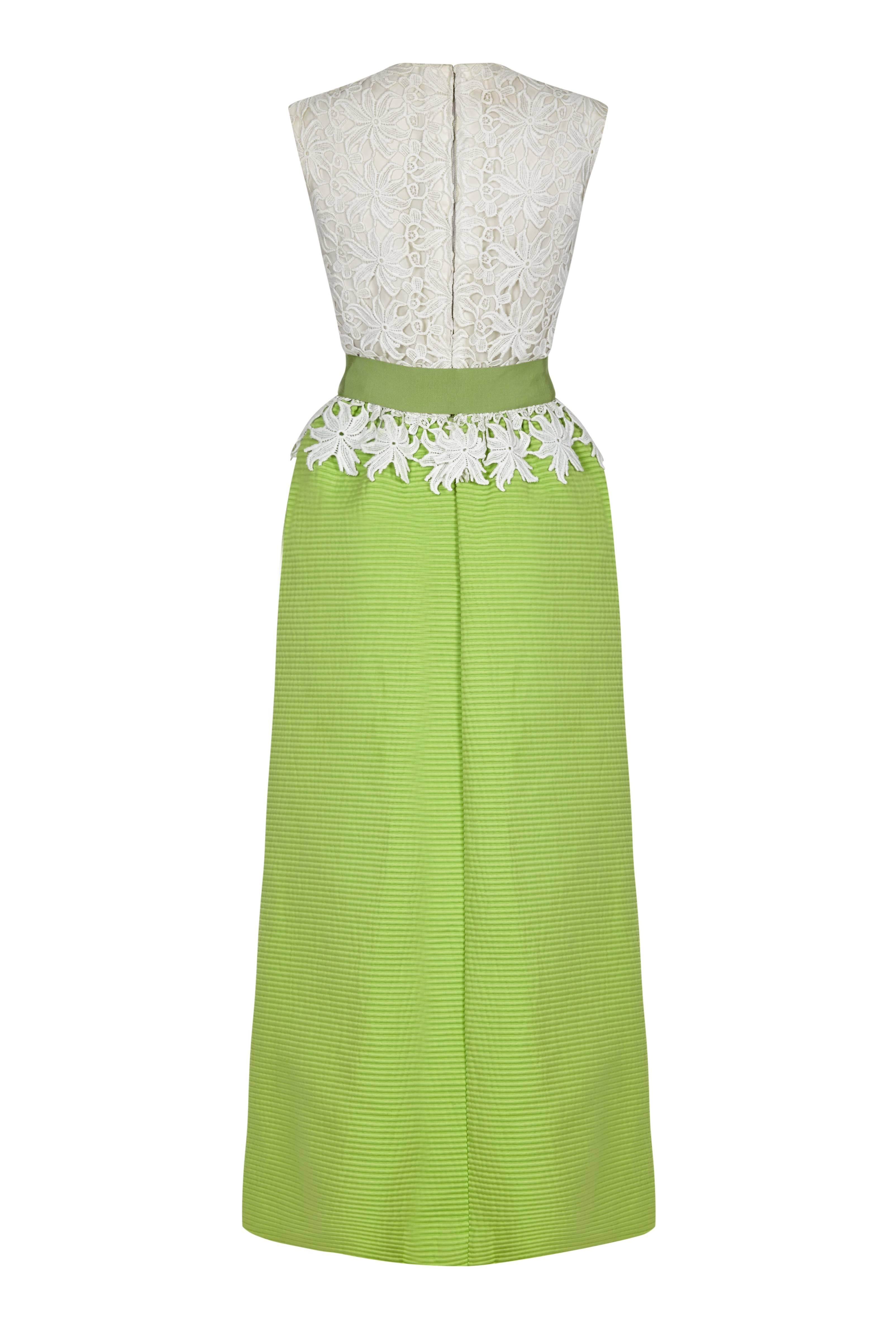This magnificent 1960s Belinda Belville occasion dress is an arresting combination of colour, texture and construction. The simple round necked, sleeveless fitted bodice has a boldly textured white lace overlay that finishes just above the hip,