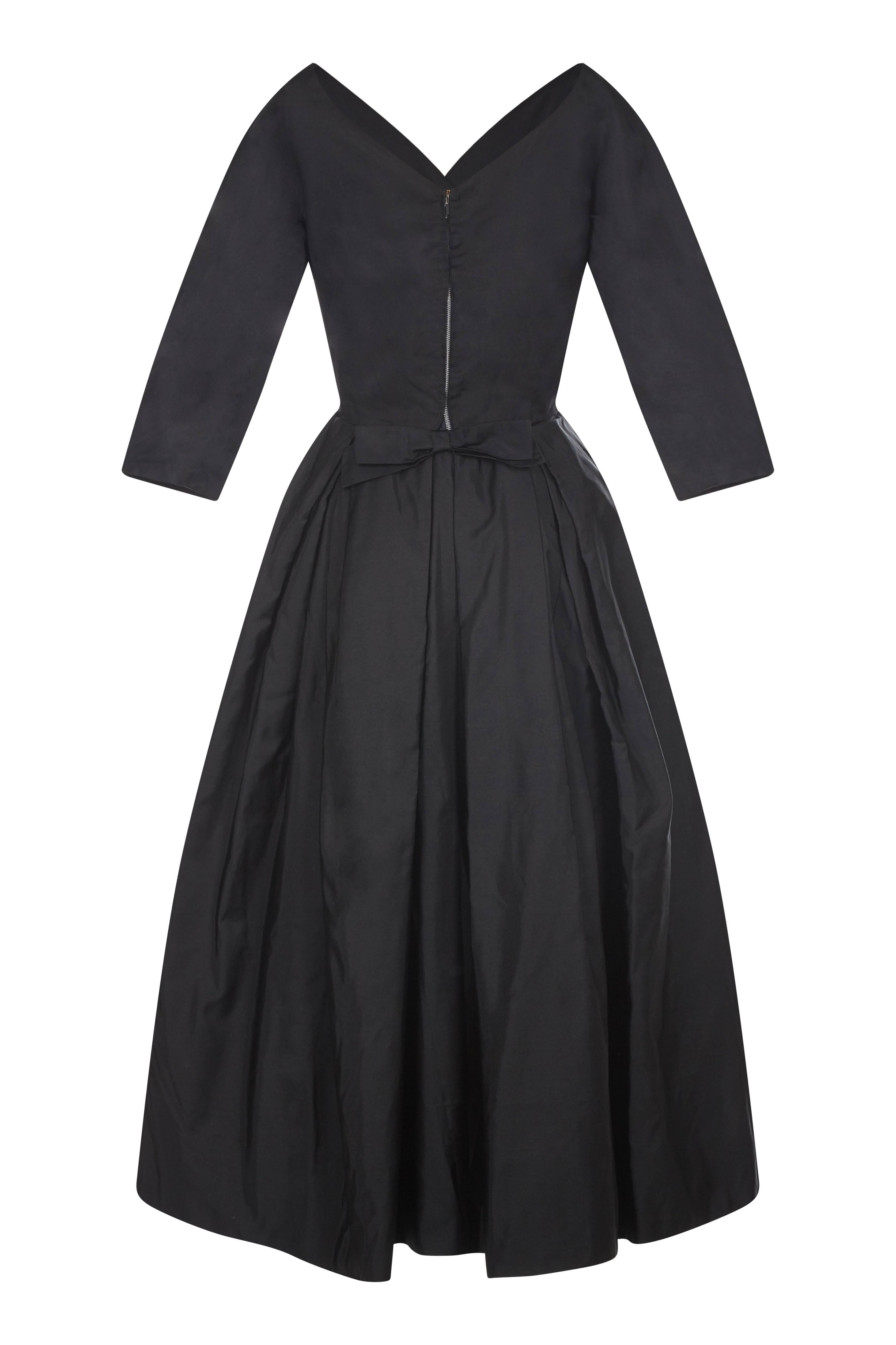 This exquisite 1950s Jean Wurtz black silk dress is a rare piece of couture of exceptional quality and style. The luxurious thick silk overlay, delicate waistline and lavishly designed skirt makes this a striking example of the elegant New Look era.