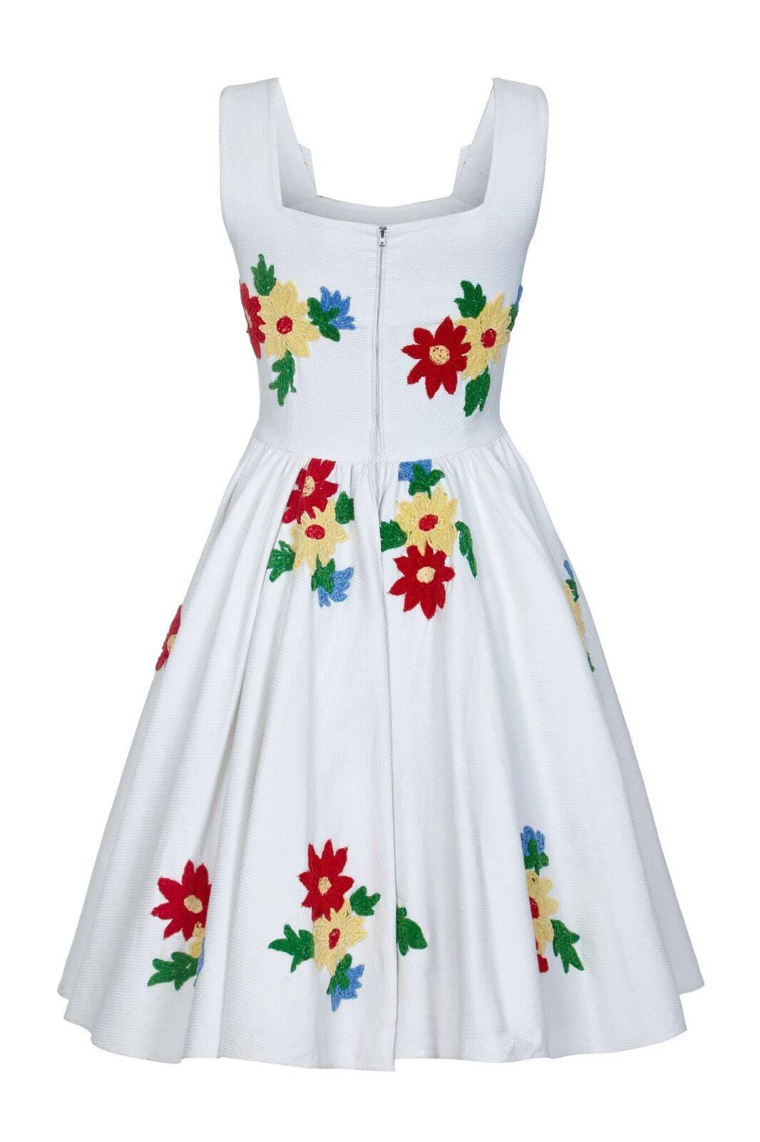 This charming early 1950s French summer dress with embroidered floral embellishment is in wonderful vintage condition. The white heavy weave cotton fabric is beautifully adorned with embroidered chenille candlewick flowers in vibrant Blue, Red,