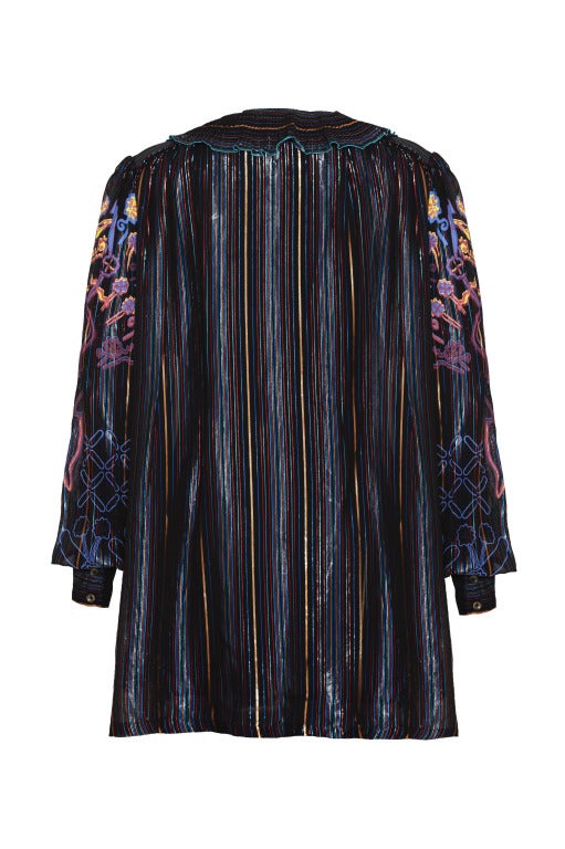 Truly one of a kind! This stunning Zandra Rhodes blouse featuring hand painted designs on the sleeves is iconic of the era. It’s crafted in an oversized unfitted style and the metallic thread running through the coloured stripes gives it a wonderful