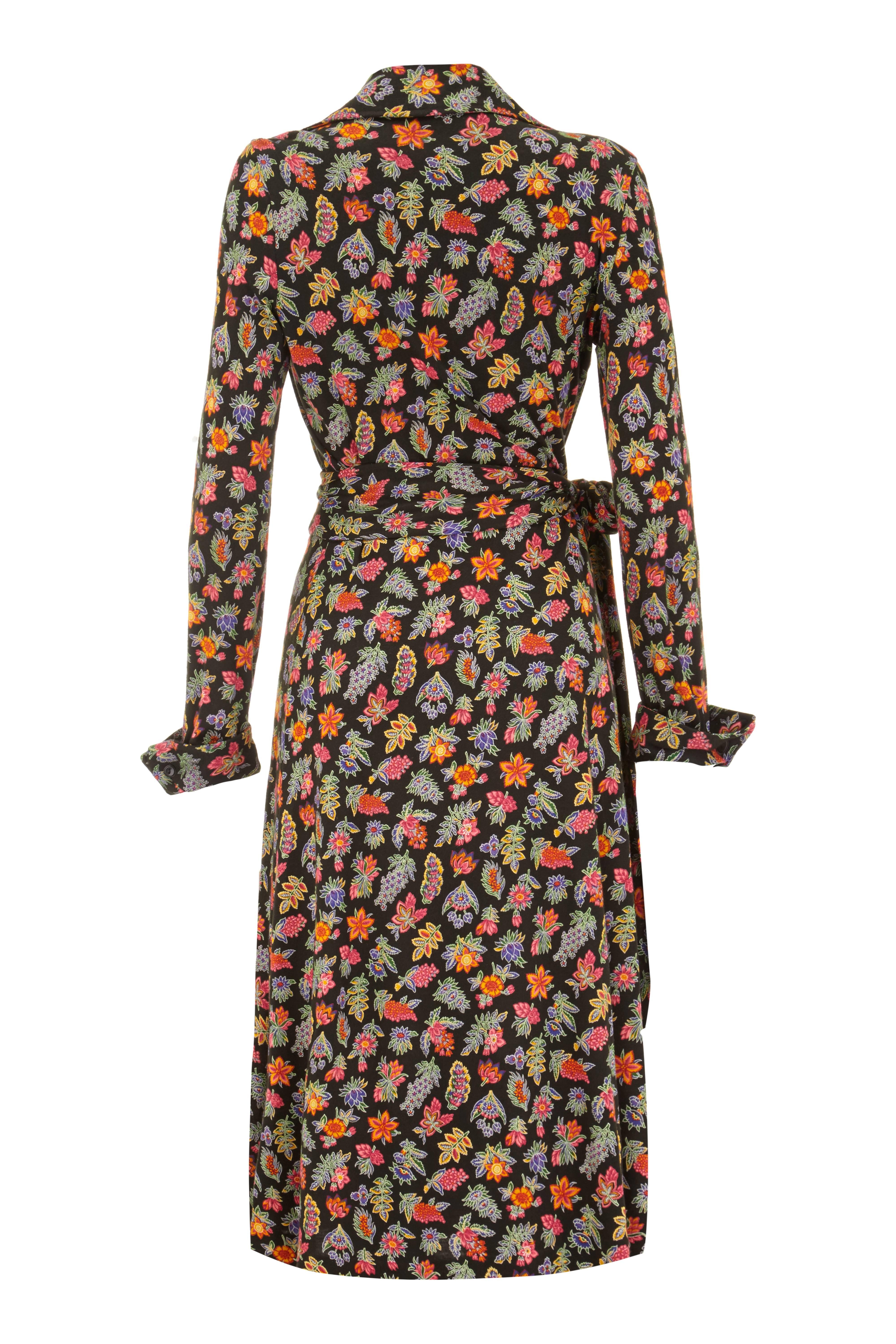 Classic 1970s vintage Diane von Fürstenberg black acrylic jersey wrap dress with colourful floral and leaf print.  This piece features long sleeves with slightly exaggerated turn up cuffs with button fastenings and wrap over front with tie