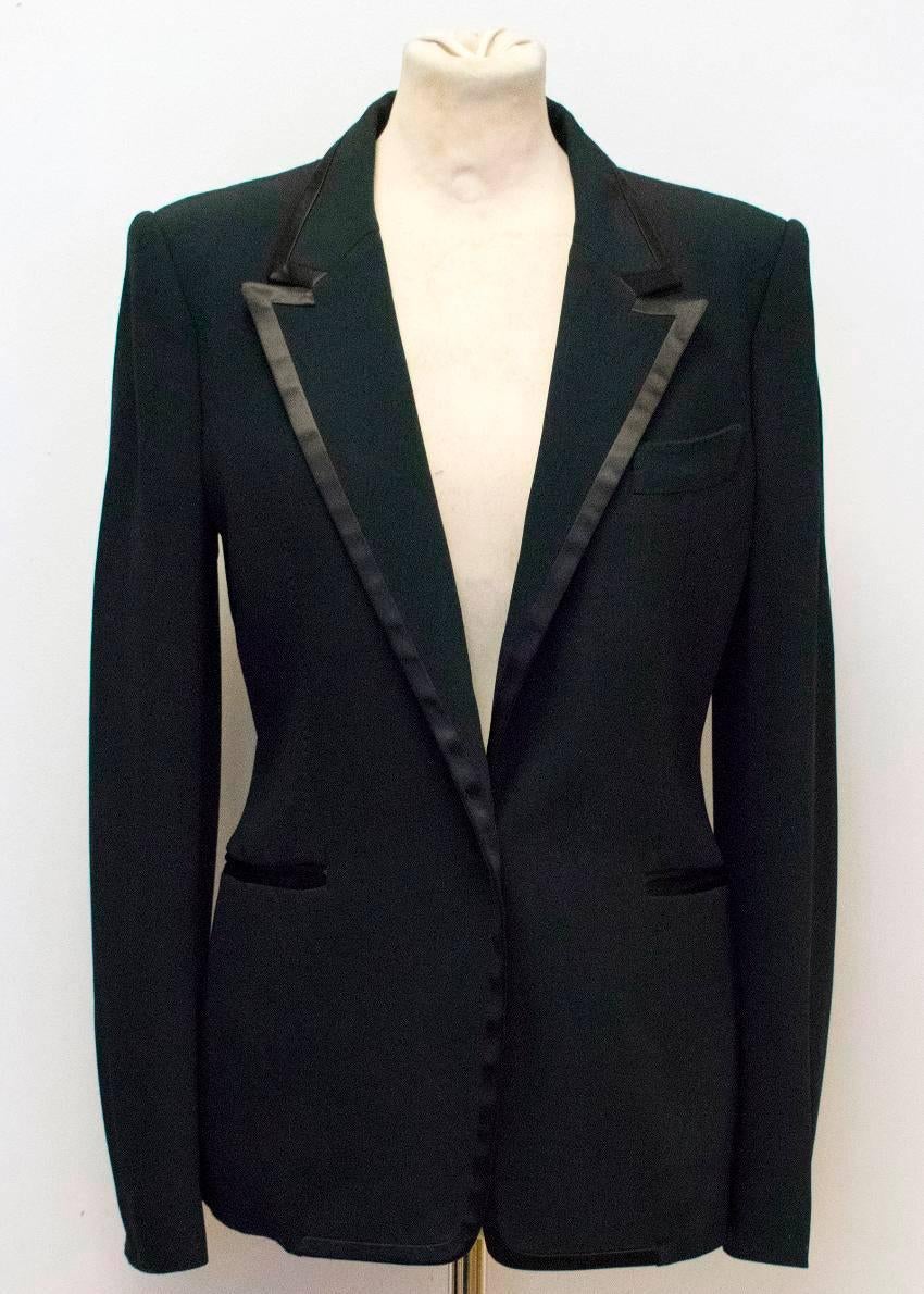 Tom Ford black slim-fitting single breasted blazer. Features peak lapels, double vent, full length sleeves, a silk trim on the pockets and lapels and a silk covered central button. Item has two exterior pockets and two interior pockets. Size