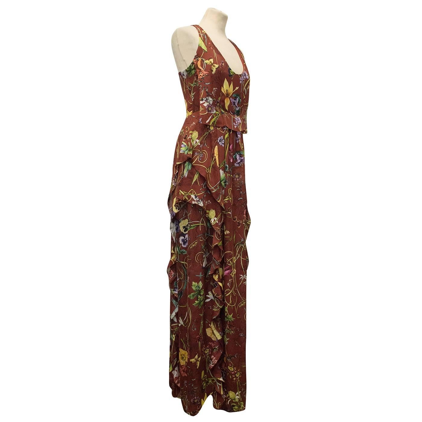 Gucci Floral Maxi Dress. The dress is brown featuring a floral print and is sleeveless with a Halter-style neck and back and a long ruffled skirt. Lined and fitted at the bust with a sheer overlay and small bustle. Size 4.

Made in Italy.
