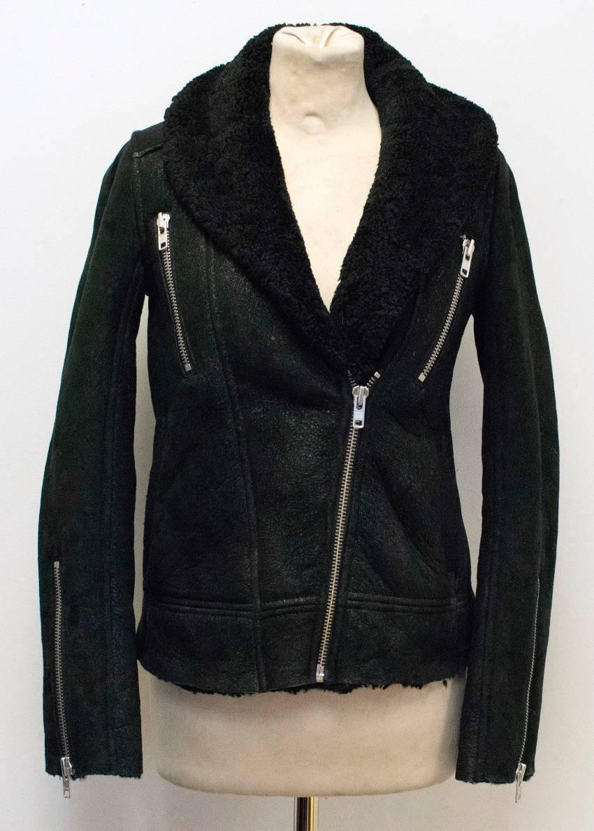 IRO black shearling biker jacket. The jacket is fully lined, has a textured effect to the outside and features silver hardware, and asymmetric front zip closure, two zipped pockets and zipper detail to the sleeves. Slim fitting with with shawl