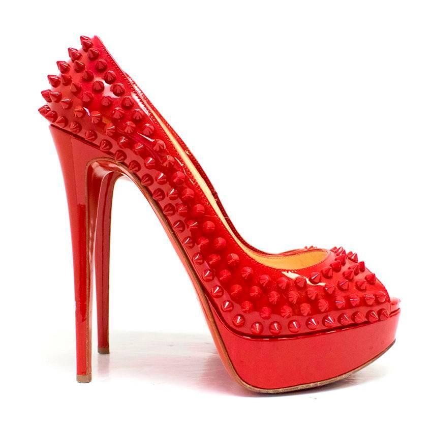 Christian Louboutin red spiked patent leather peep-toe pumps. These shoes features spikes throughout the body of the heels. The soles are the signature red and the inner soles are composed of tan leather. These shoes have a peep toe, 3cm platform,