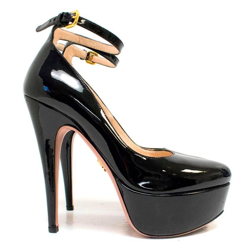 Prada black patent leather Mary Jane platform pumps. These shoes feature a tan leather inner sole and a beige outer sole. The Prada logo can be seen on the bottom sole. There is a strap with a gold buckle around the ankles. 

Condition: 9/10 The