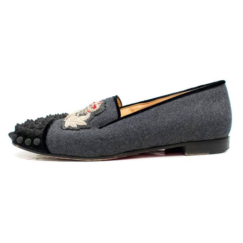 Christian Louboutin ladies grey spiked embroidered loafers. These shoes feature a grey spiked toe with embroidery on the top of the foot. The lining is composed of velvet. The inner lining and sole is tan leather and the outer sole is red.