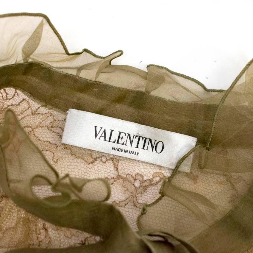 Valentino khaki coloured delicate lace see through long sleeved jacket with floral embroidery, a banded collar with ruffle detail and a silk ribbon that ties into a bow. Fastens at the front with buttons concealed under a silk panel. 

There are