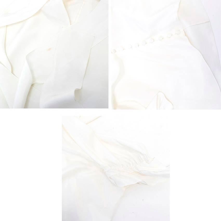 Yves Saint Laurent cream silk loose fit blouse  with short bishop sleeves, ruffled cuffs, ruching  details on the shoulders and a high neckline with a ribbon tying around the collar and a cut out detail on the chest. 
Fastens at the front with