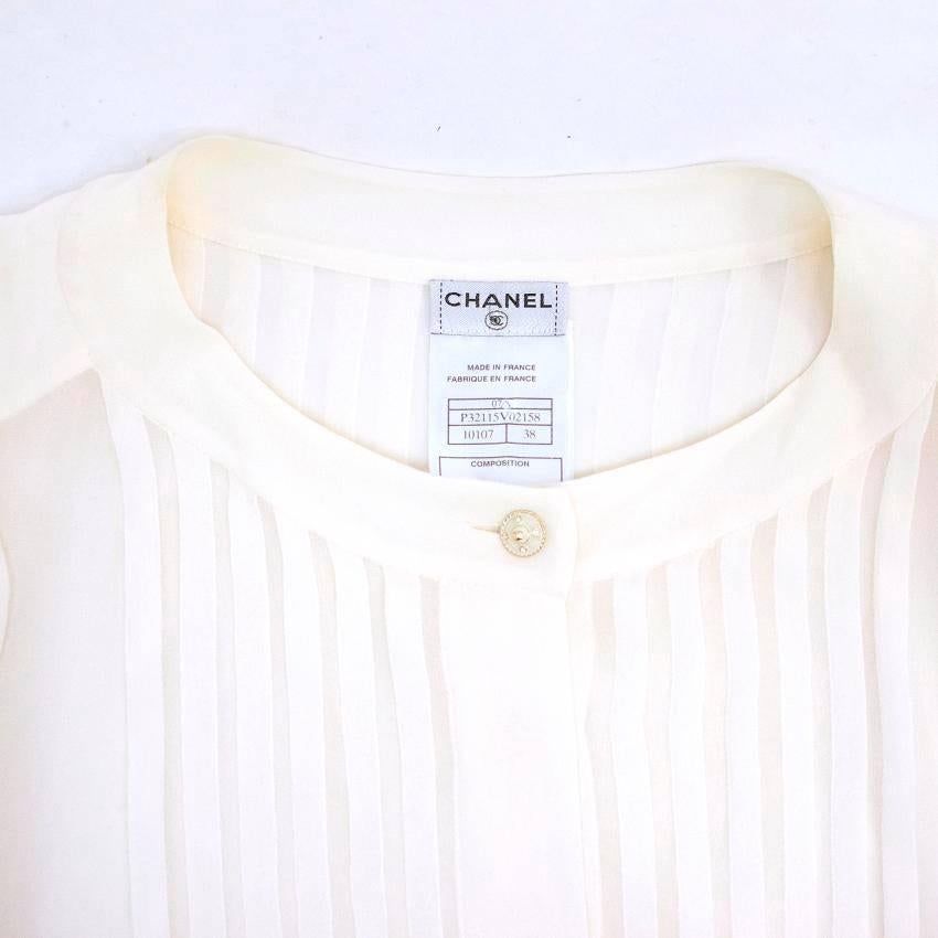 Chanel cream silk long sleeved blouse with ruffled hem, a banded collar with a cream enamel button and pleats on the sleeves and on the front. Featuring a silk ribbon belt around the waist.

Condition: 10/10 

Size: S
Size UK: 10
Size US: