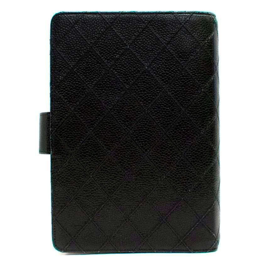 Chanel black embossed leather mini ring binder organiser. It features two interior pockets, gold hardware and a popper close with the Chanel logo on it. 

There is slight wear to the exterior leather and the metal hardware is slightly tarnished,